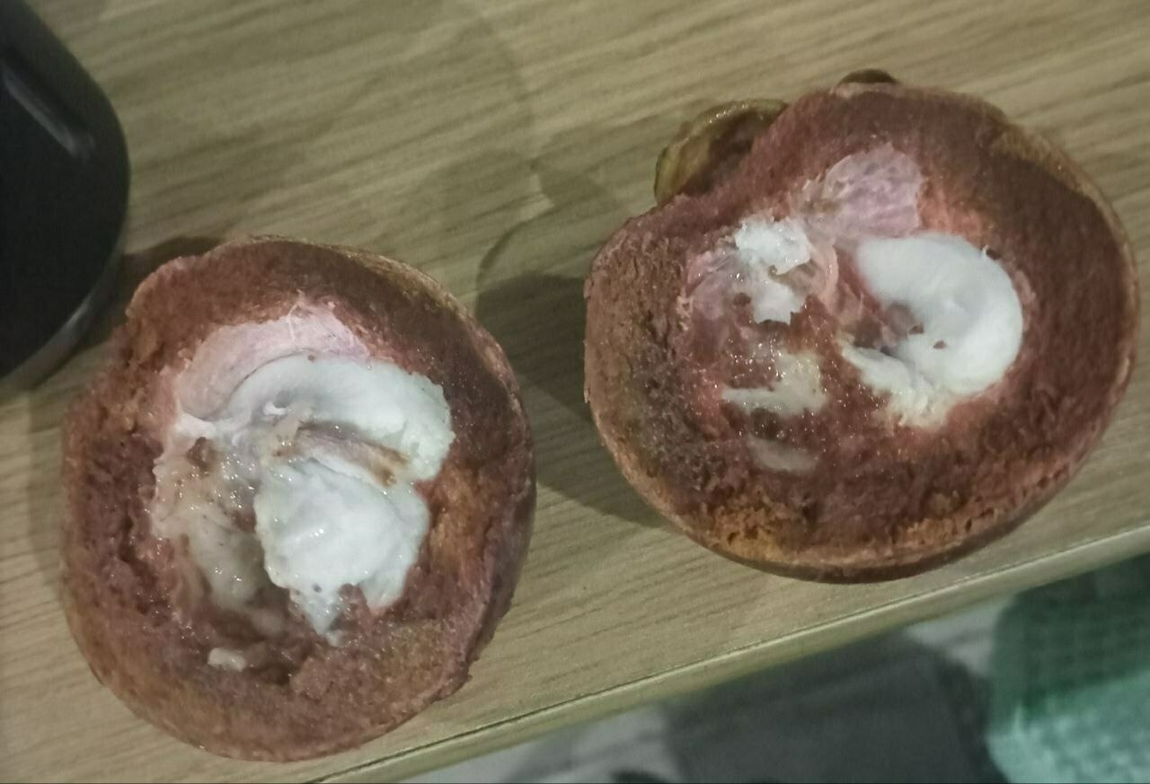 cut-open mangosteen with both halves face-up, with the white fruit inside a little mushy 
