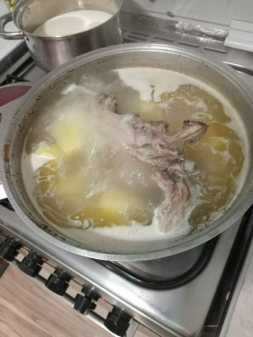 meat and potatoes boiling in a large pot on the stove