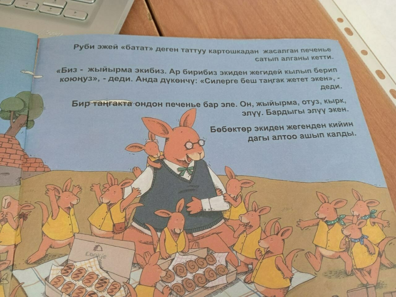 page in a picture book. one kangaroo teacher surrounded by many small kangaroo students. Kyrgyz text on upper right