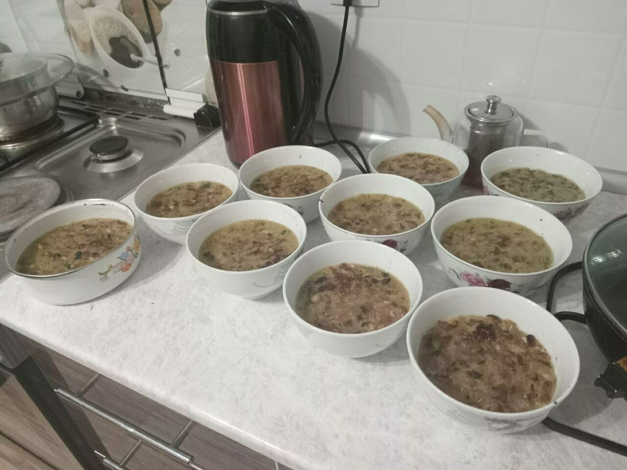 9 soup bowl and one small, circular tin all filled with fat jelly and some ingredients in it (meat and onions maybe)