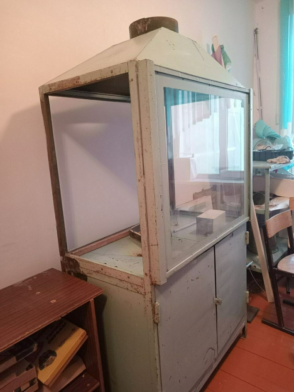 an old fume hood-looking piece of equipment amongst other things in a small storage room