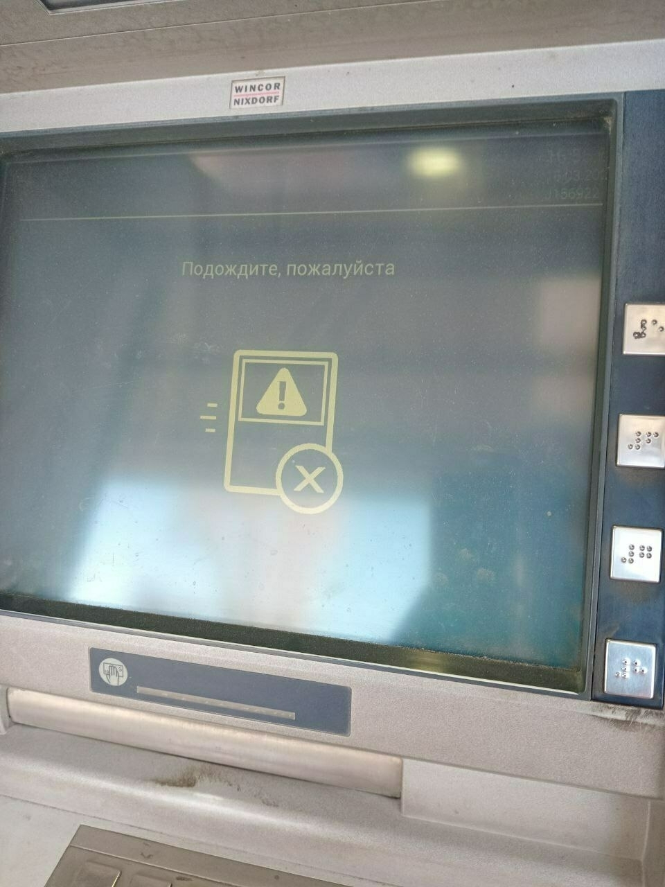ATM showing what looks like an error graphic with the words "подождите, пожалуйста" ('wait, please' in Russian)