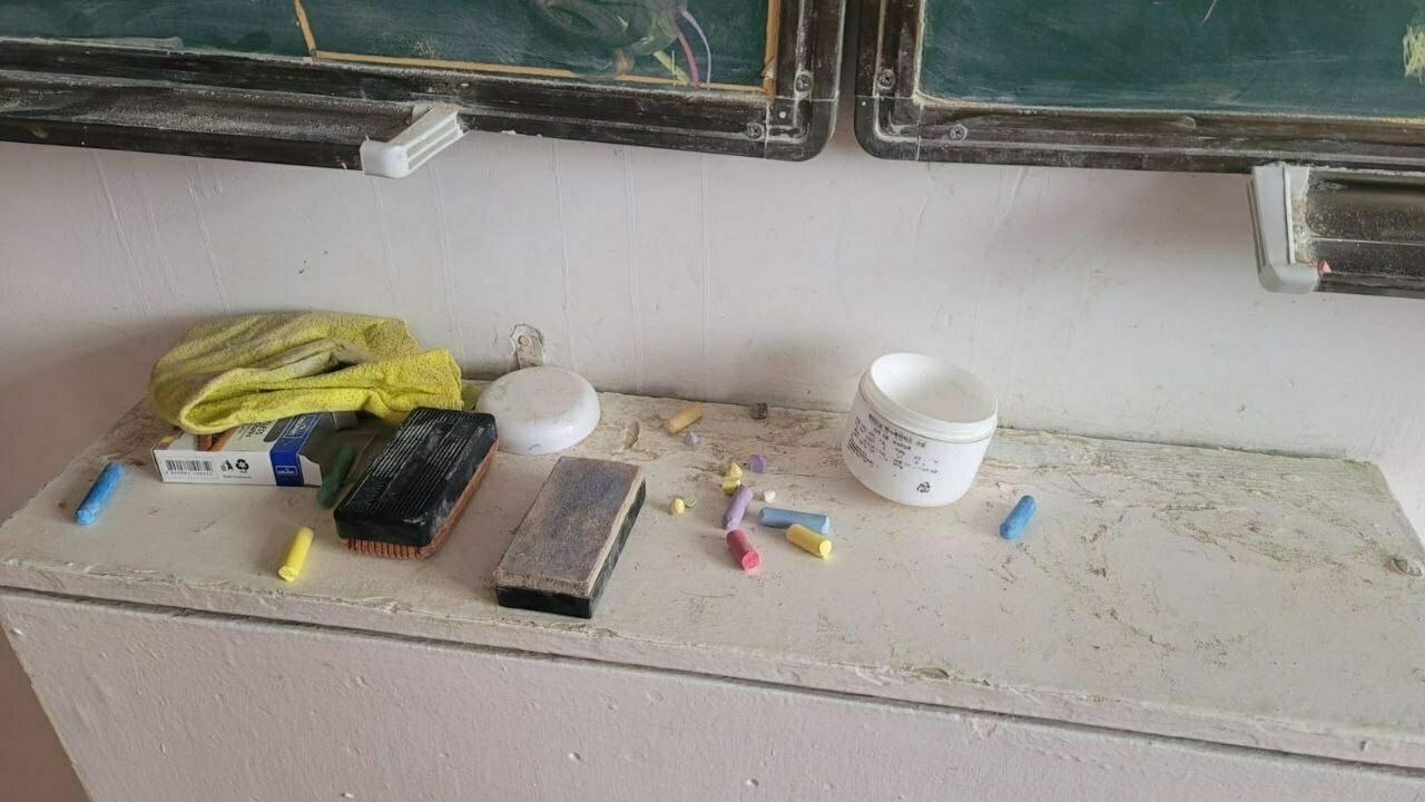 broken pieces of colored chalk haphazardly strewn about a narrow, white counter top