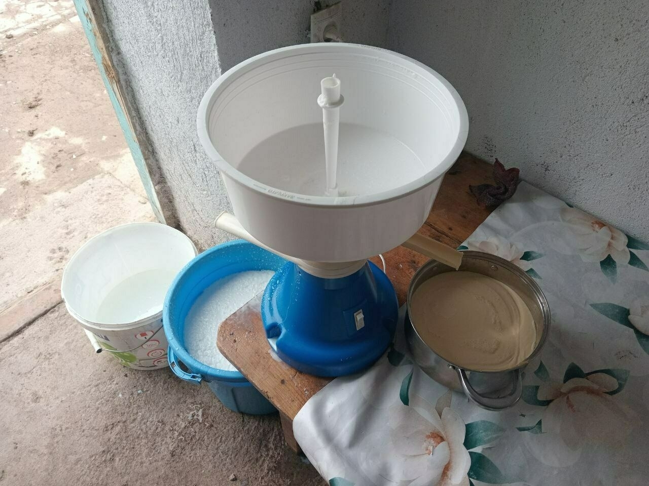 plastic blue and white separator, with milk coming out and going into a separate blue bucket on the left side, and yellowish cream coming out and going into a pot on the right
