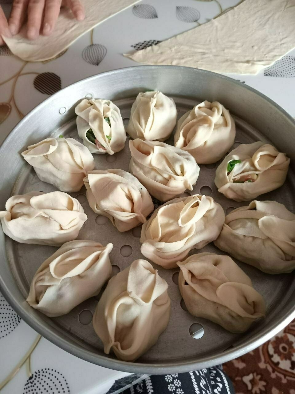 formed and filled manti (dumplings) in a metal steamer layer