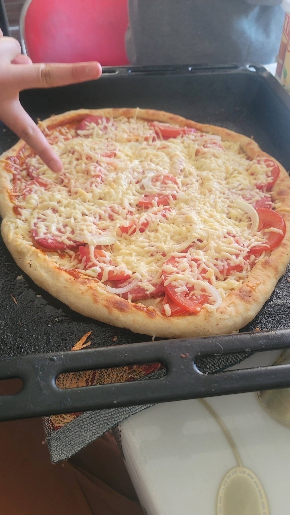 baked pizza on a black oven shelf with a peace sign on the left