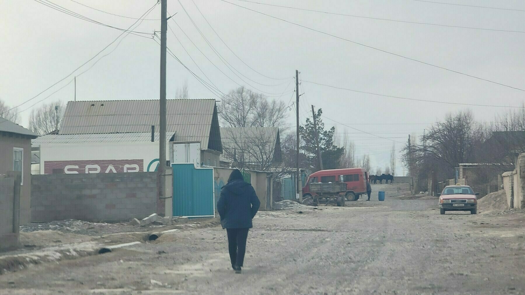 view down a village street, with several houses on the right. spar truck visible inside the fence of one of the houses