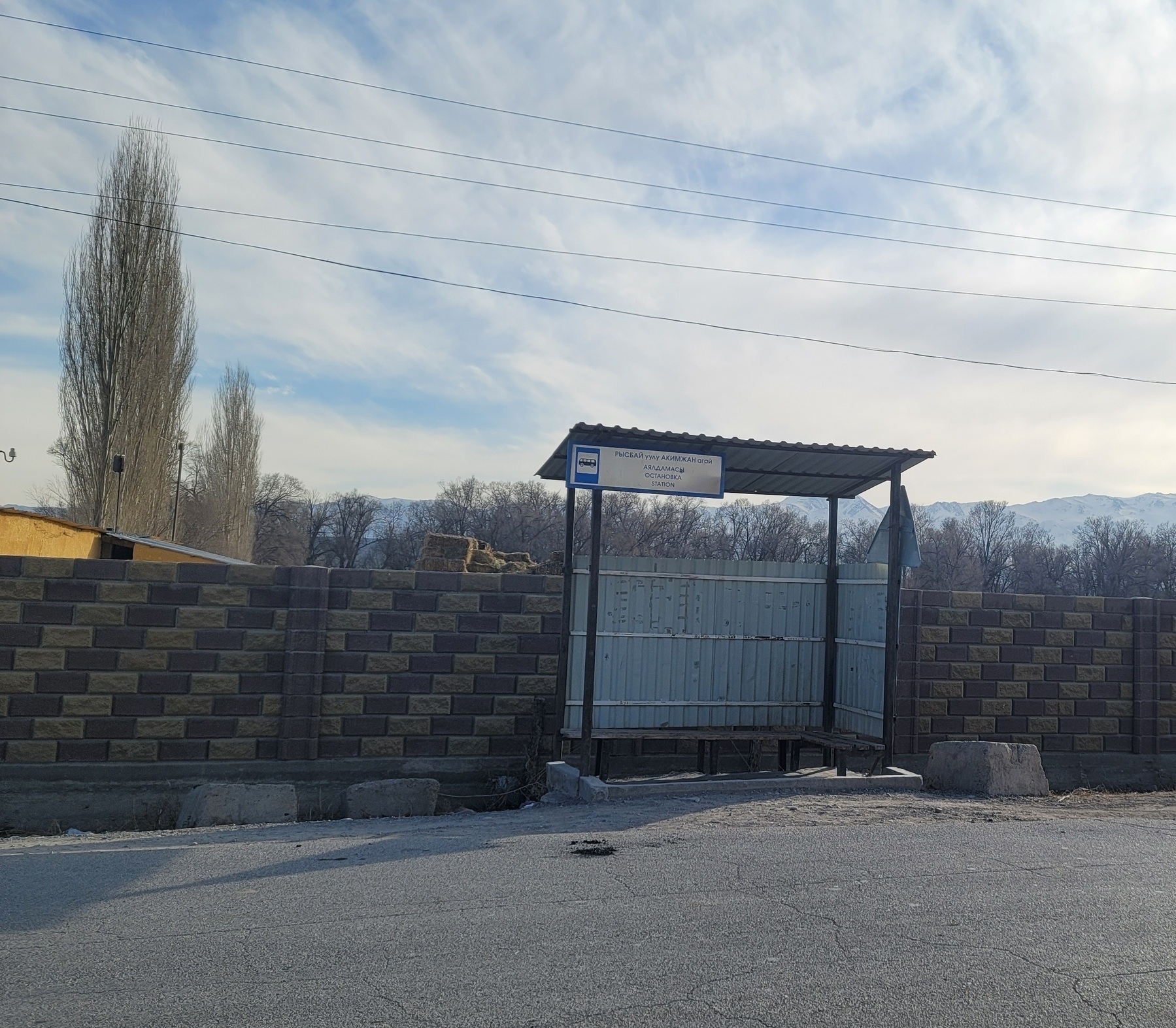 small, old bus stop with low, wooden benches, two tin walls and a tin roof