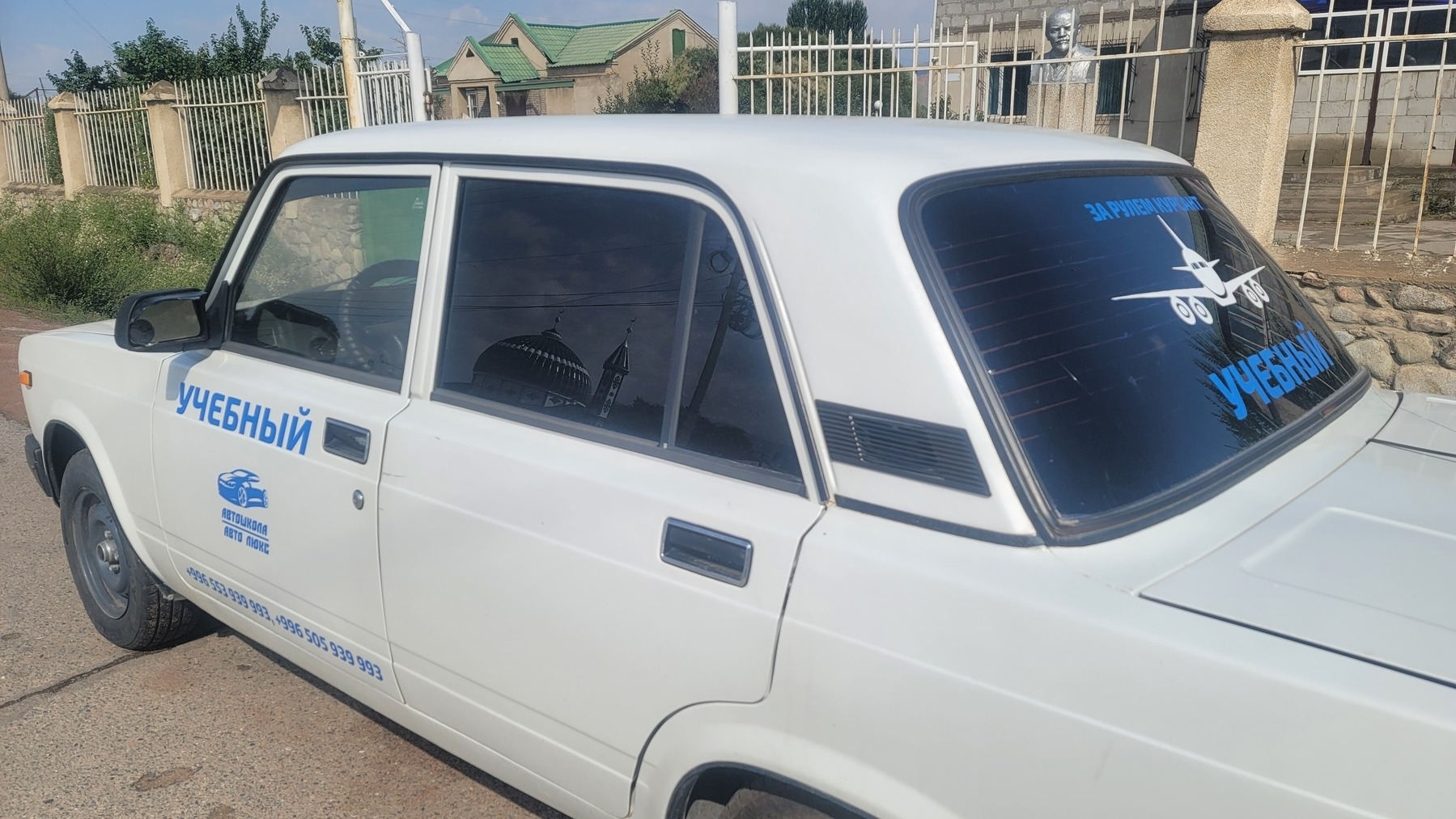 white car with blue Russian text, denoting that it is a student driver car