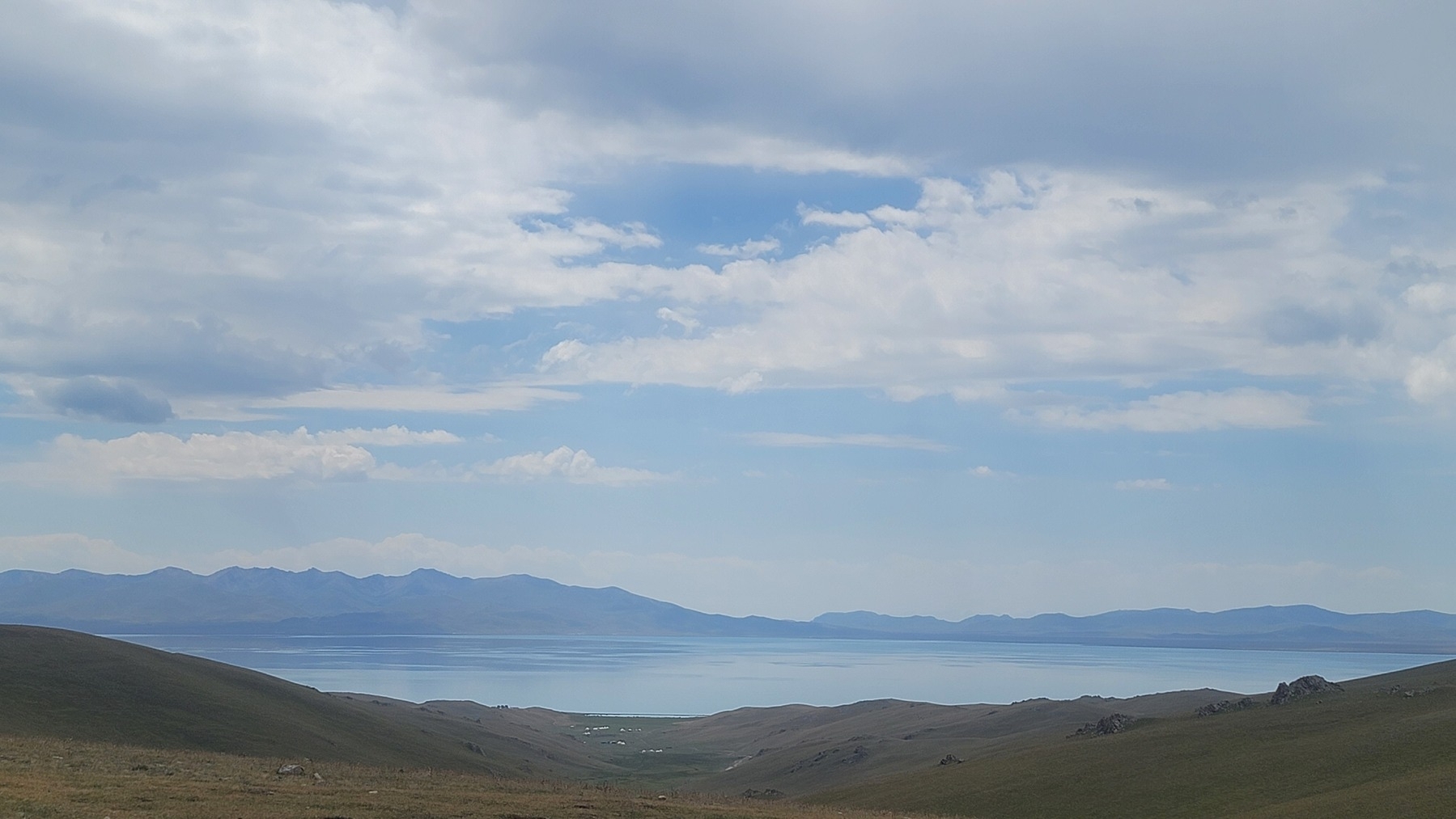 Looking down at a descending valley leading to a lake. Mountains in the background