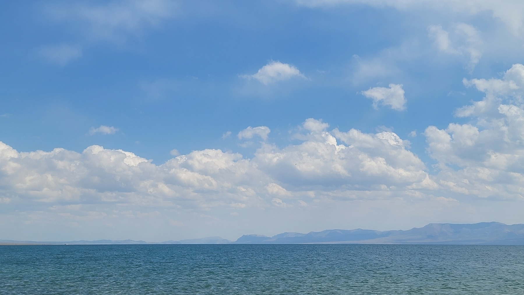 blue lake water with mountains in the background on the right