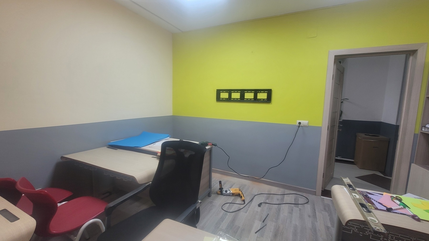 black metal rack to hold a smartboard nailed to a classroom wall