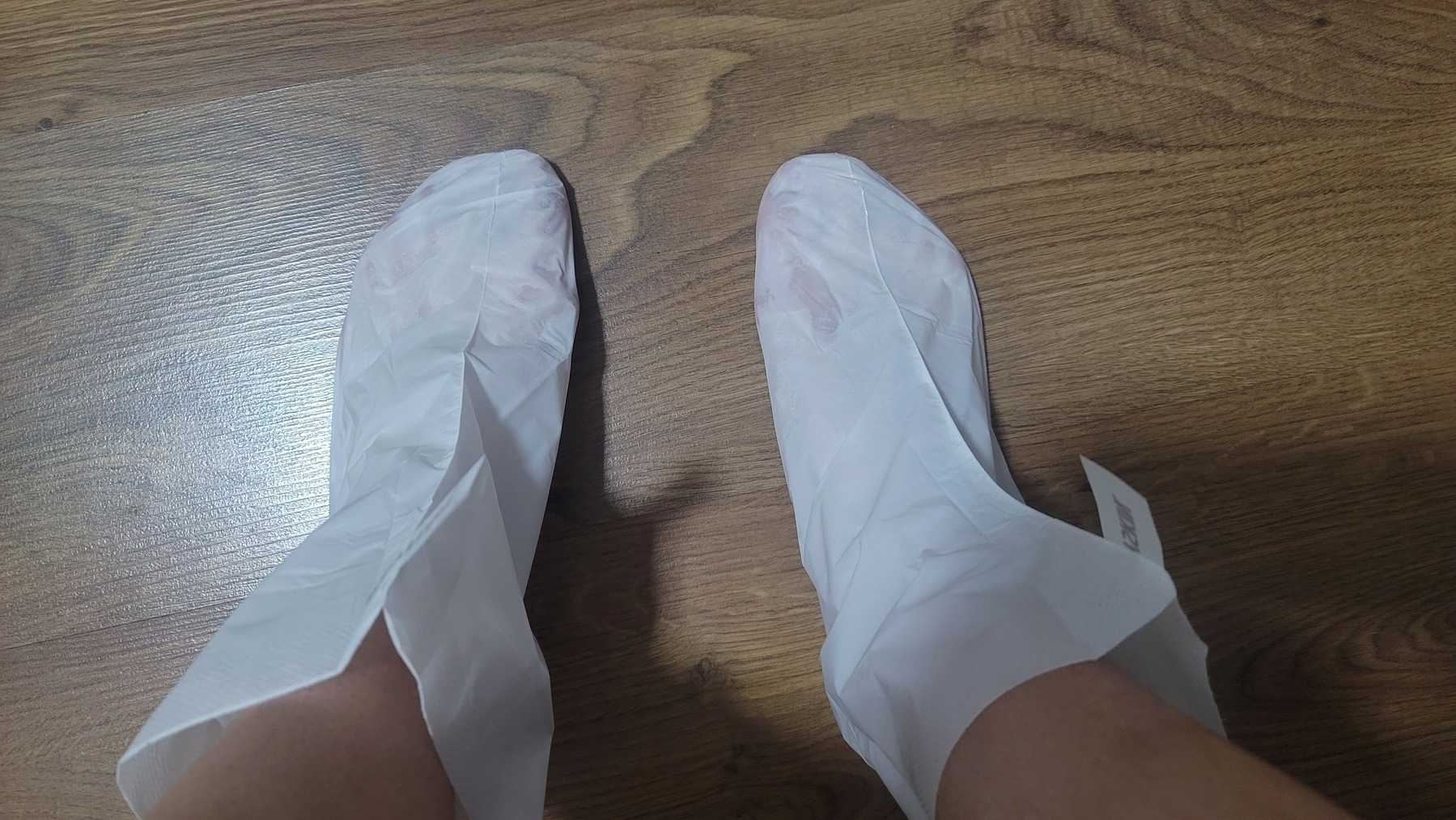 feet, each inside a boot made of what looks like white face mask material