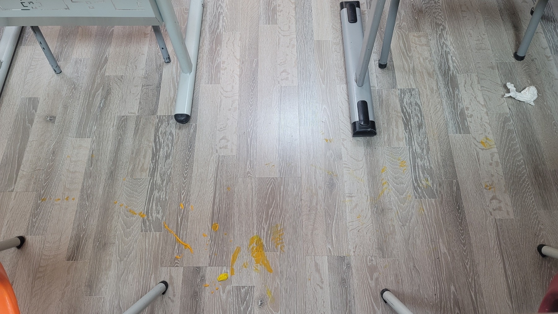orange and yellow paint on a light gray/brown classroom floor