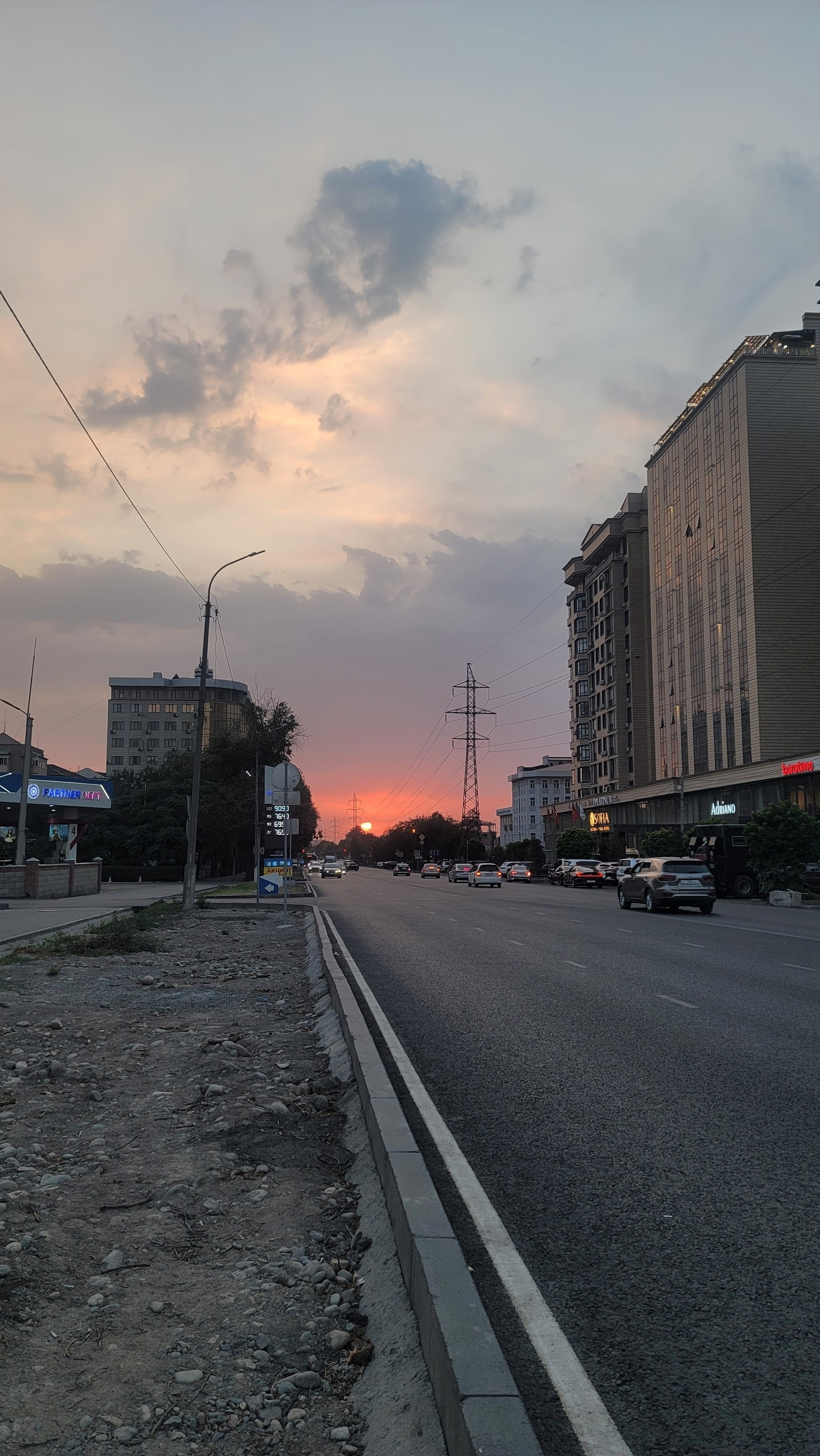 pink/orange sunset visible at the end of a city street