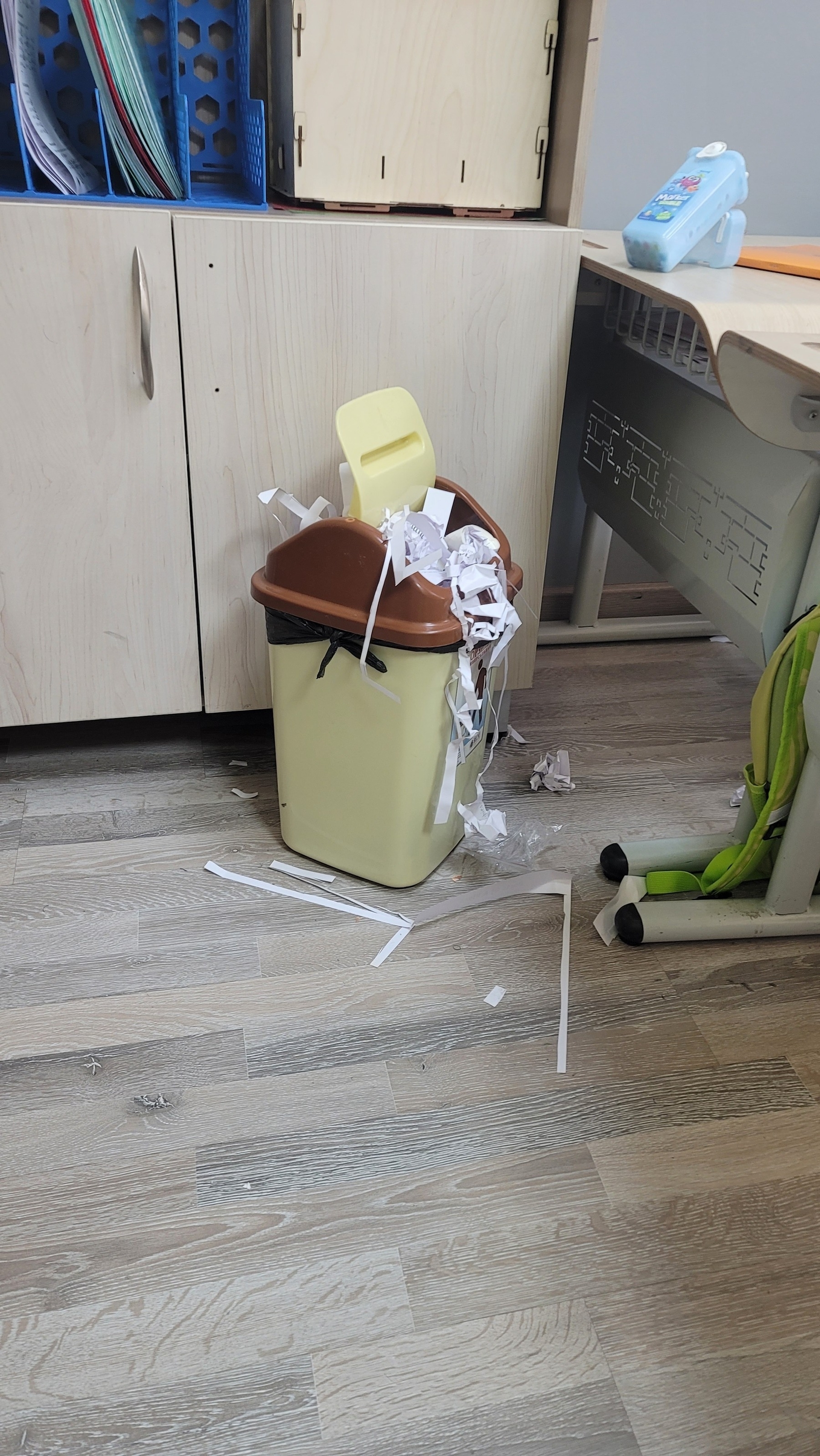 small trash can overflowing with scraps of paper