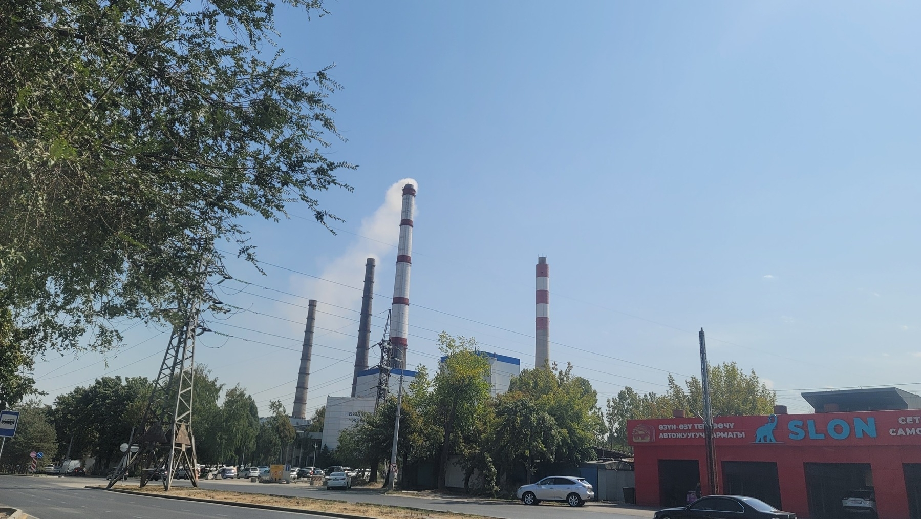Building with four smoke stacks visible across the street, close to a car repair shop