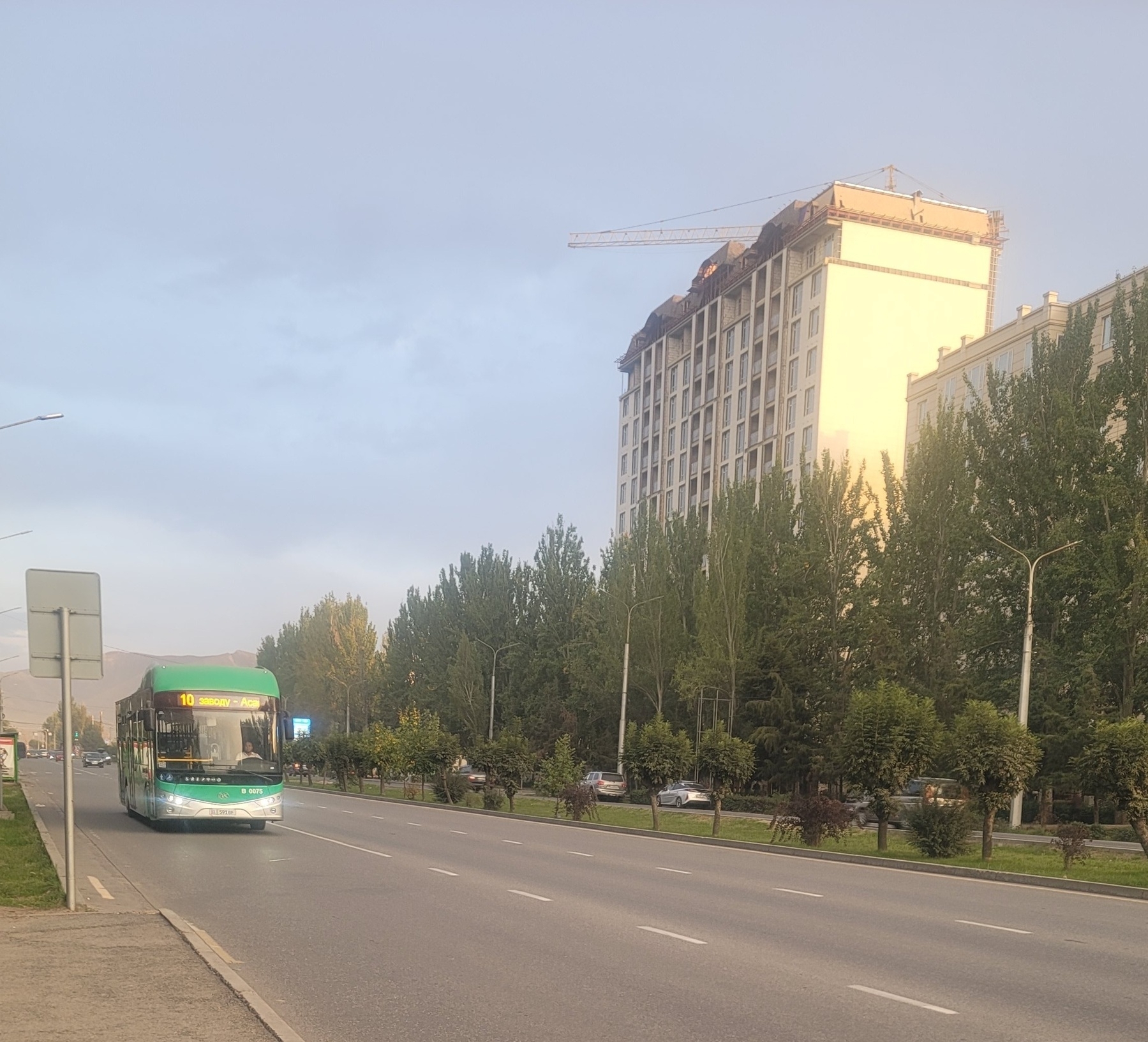 green bus driving down a road, approaching the foreground