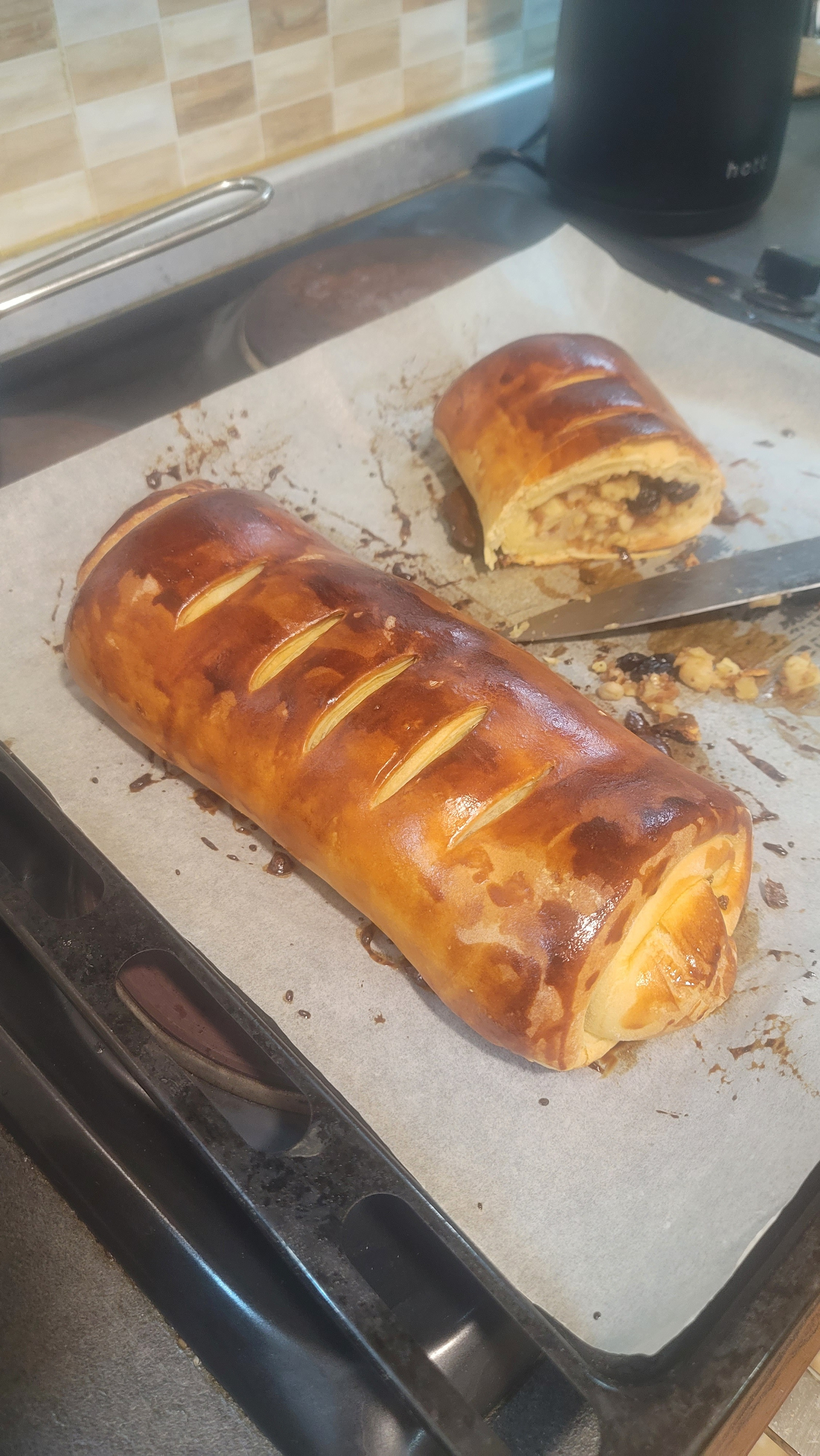 One and a half strudels on a baking pan with a piece of baking paper on it