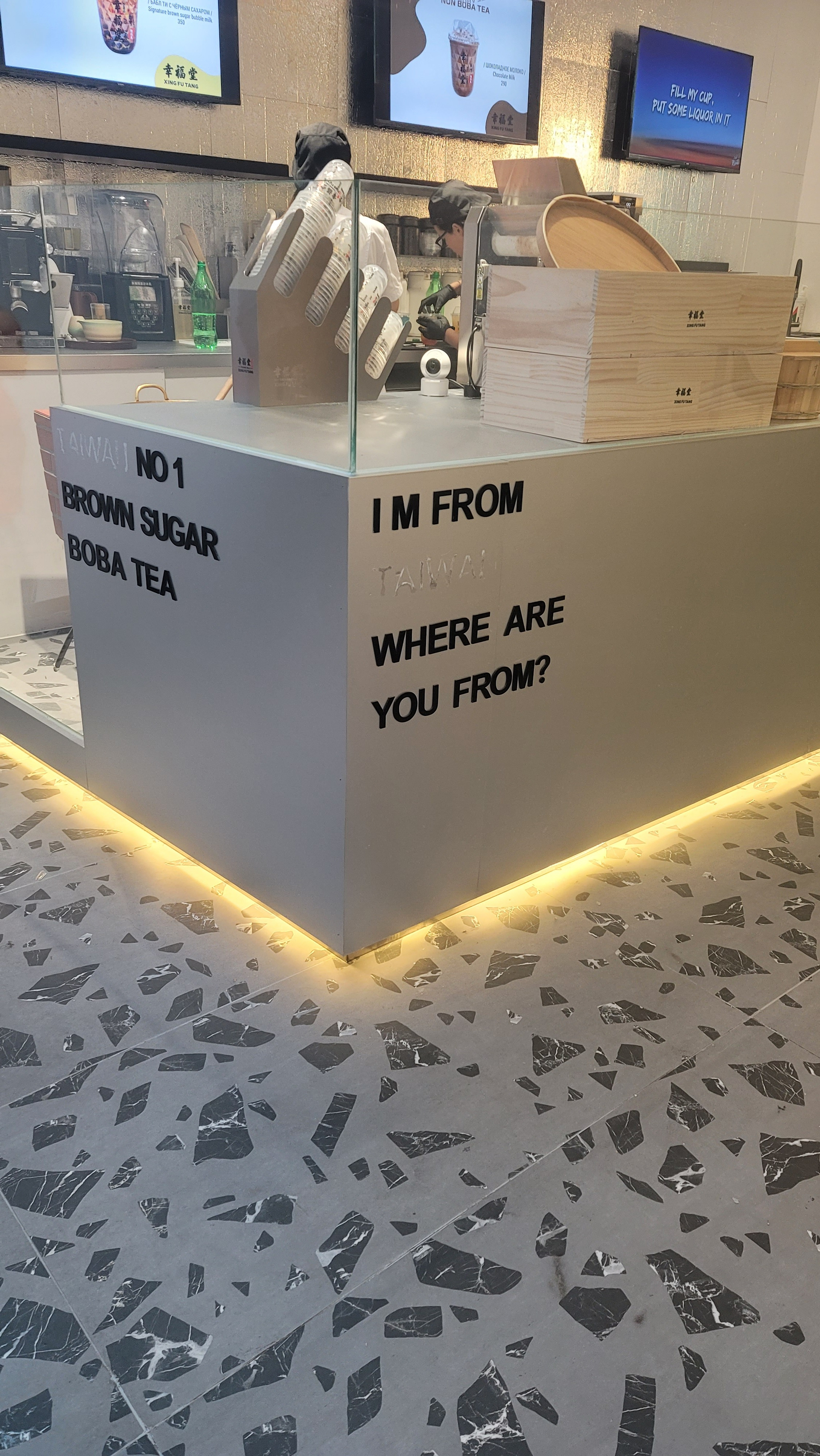 White boba tea counter with black letters affixed to it: "I'm from ... where are you from?". Outline of "Taiwan" visible after "I'm from", but no letters there, just the residue of letters which were there before