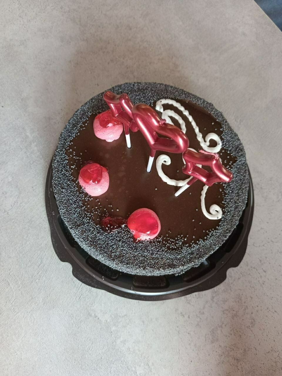 Small chocolate cake with three red candles 