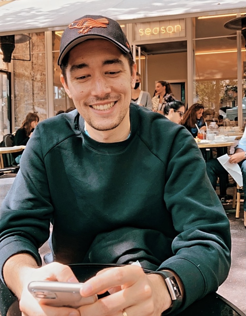 a photo of myself, sitting at the table of a café, with my phone in hand and a smile on my face