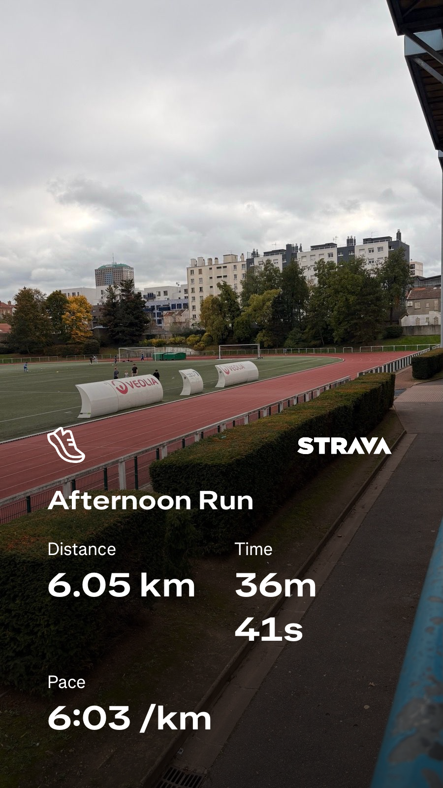 A running track in an urban park is shown with overcast skies, alongside a Strava activity summary of a 6.05 km run taking 36 minutes and 41 seconds at a pace of 6:03 per kilometer.
