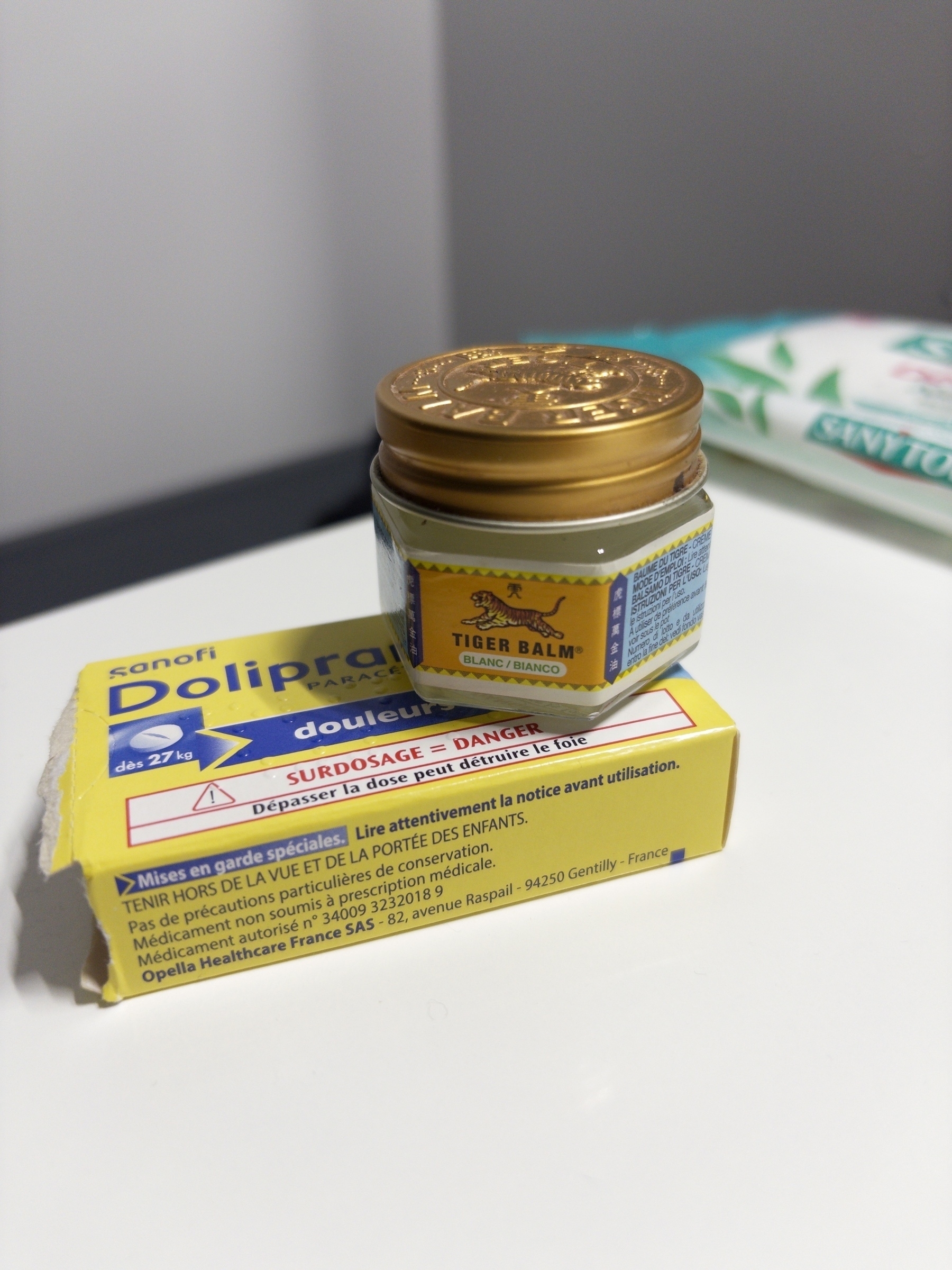 A jar of Tiger Balm is placed on top of a box of Doliprane medication.