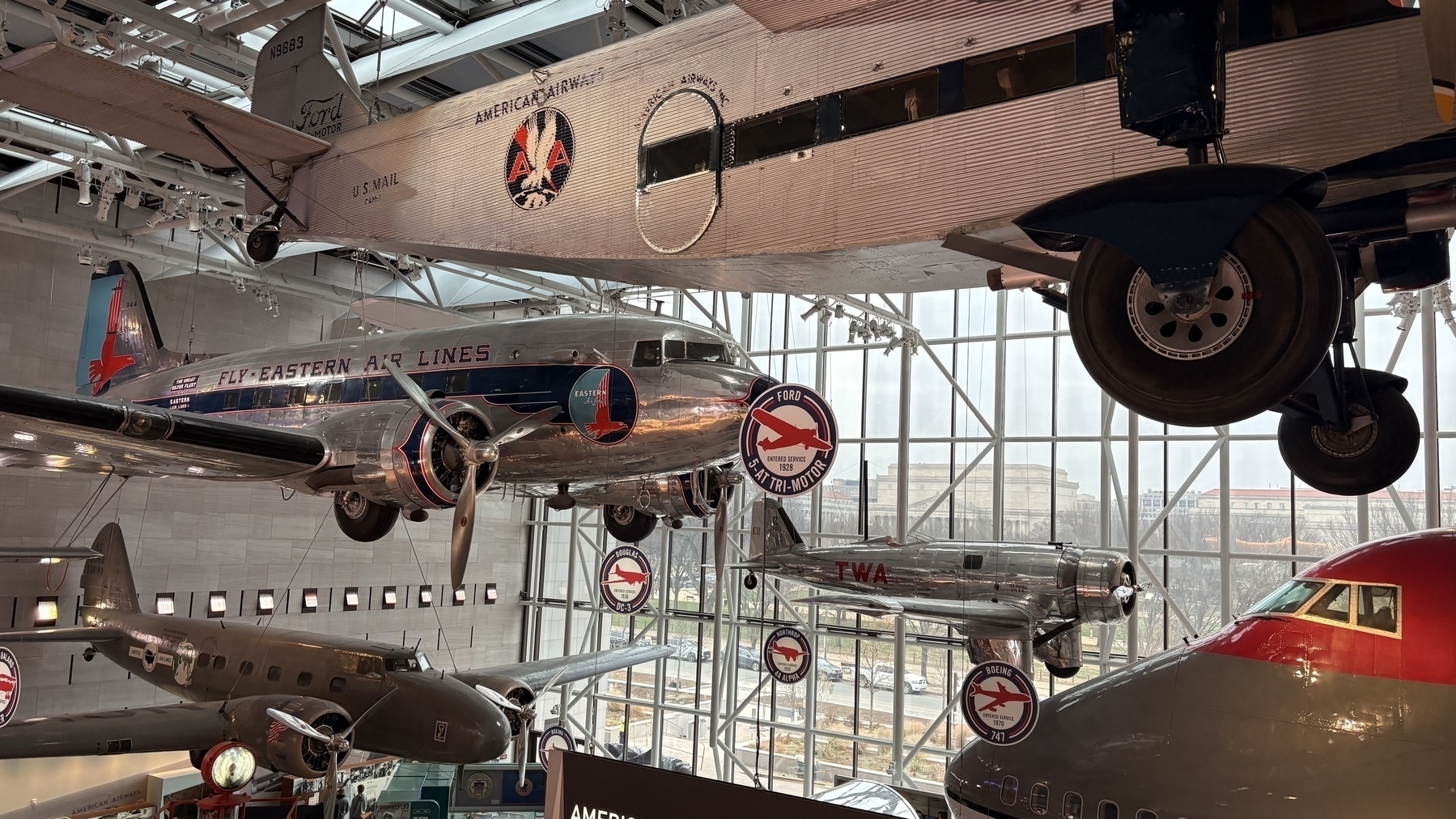 Several vintage airplanes are displayed inside a museum with signage indicating different airlines.