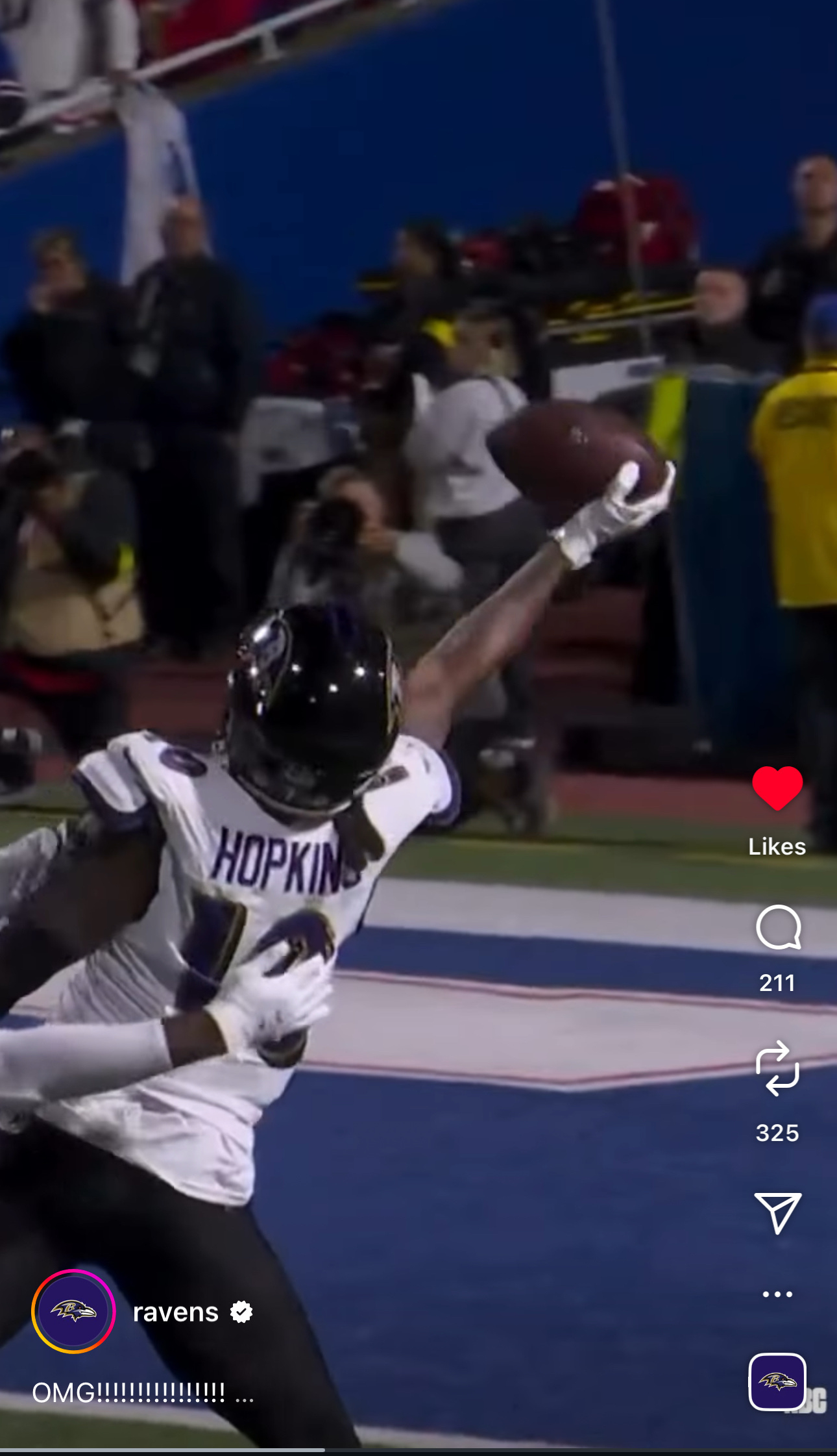 A football player in a Ravens jersey makes a one-handed catch on the field.