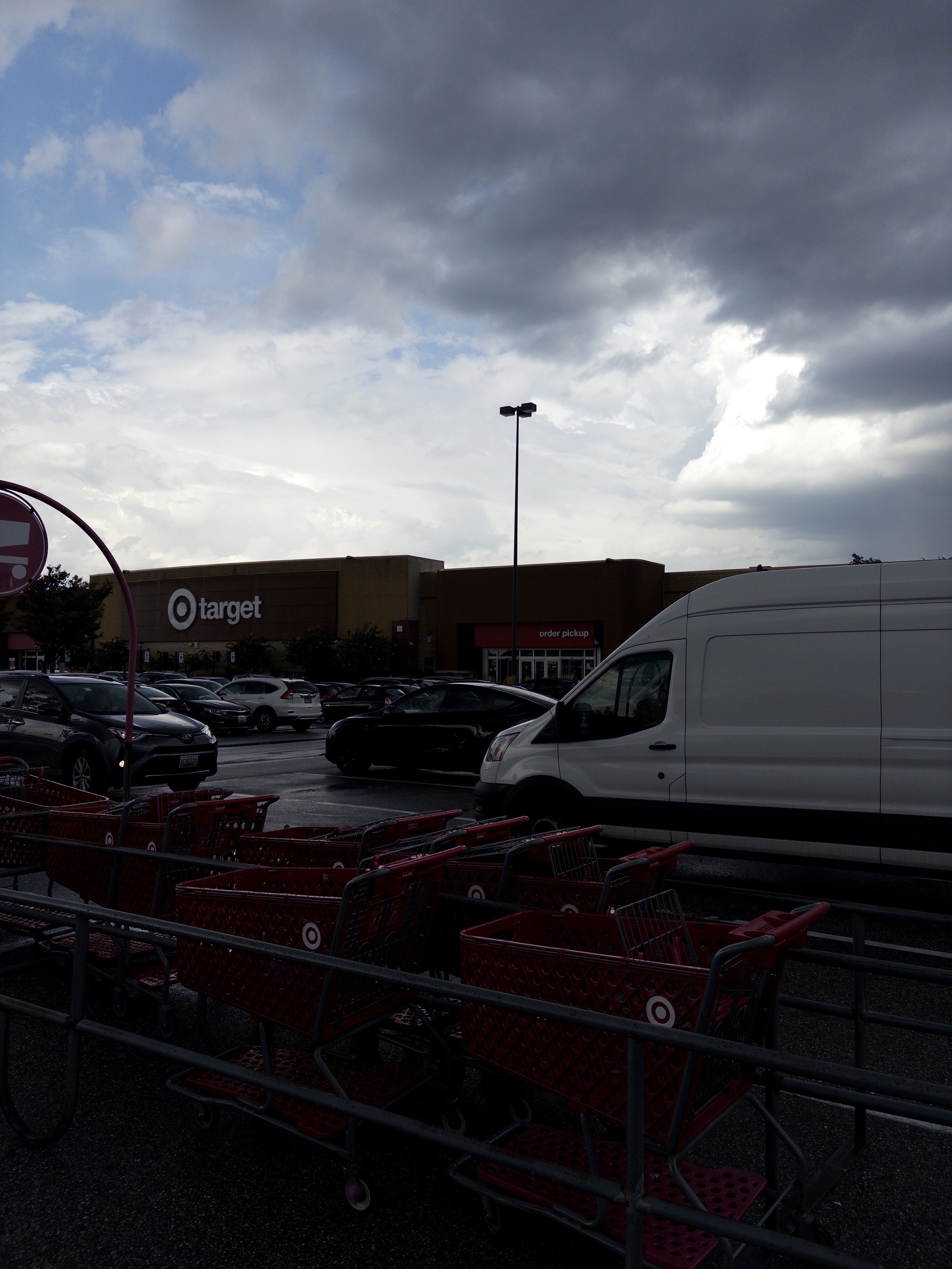 Shopping carts are lined up in a parking lot in front of a Target store under a cloudy sky.