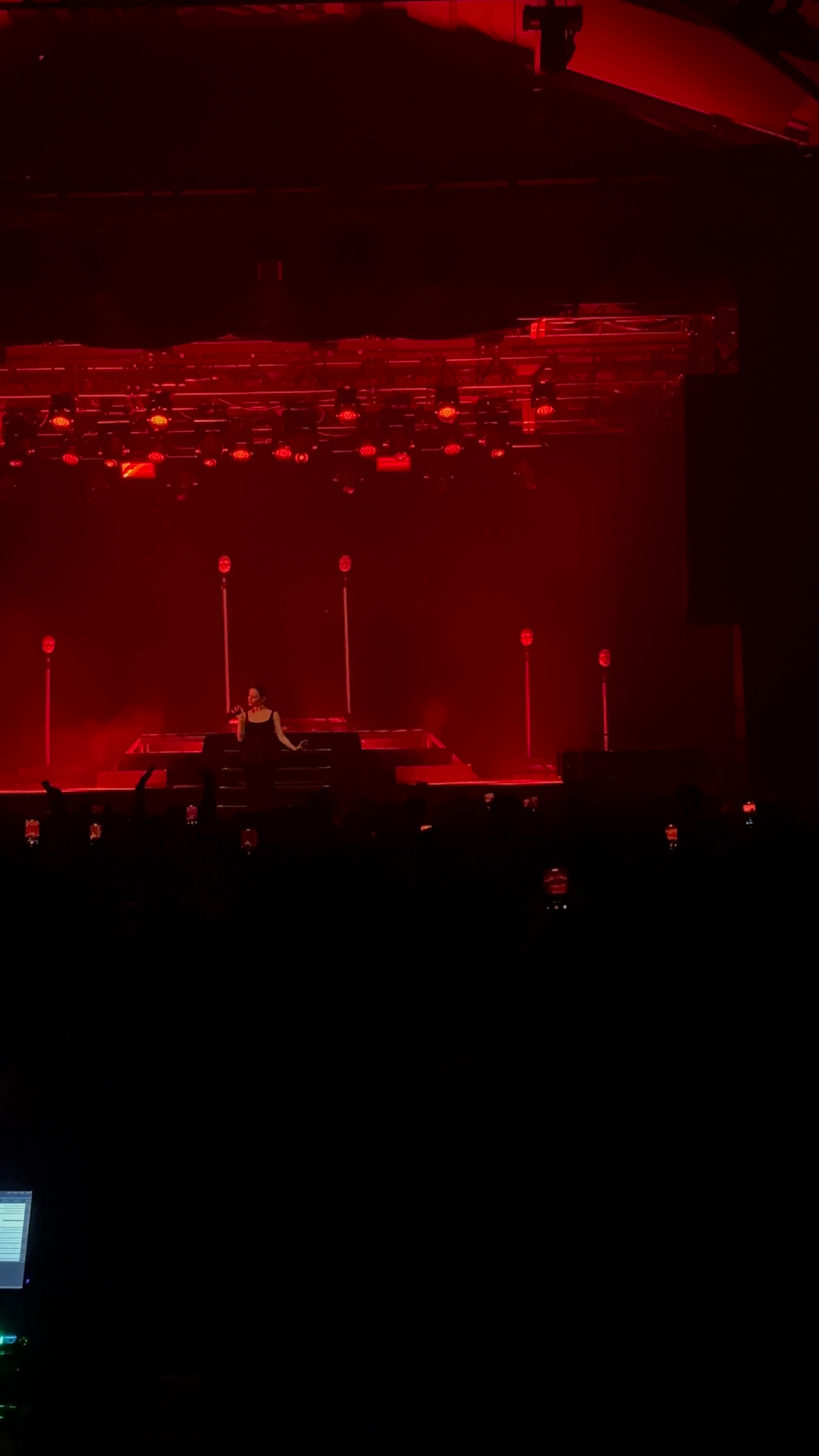 A performer on stage is illuminated by red lighting amidst a dark background.