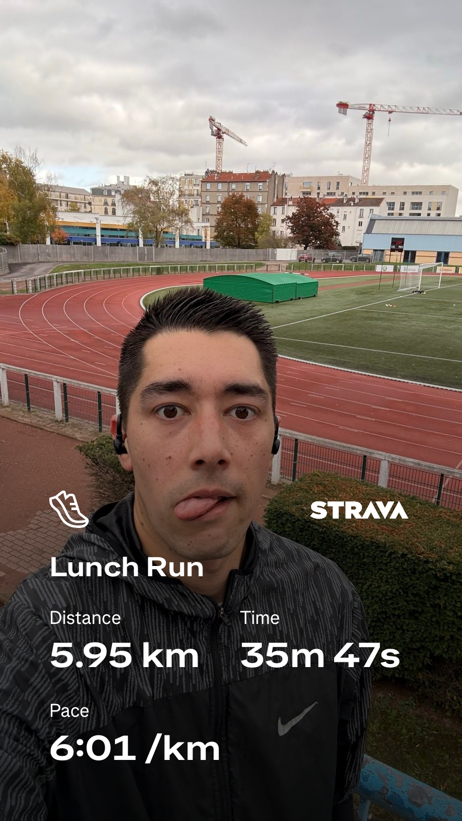 A person is taking a selfie in front of a track field, with Strava stats overlay showing a run of 5.95 kilometers in 35 minutes and 47 seconds at a pace of 6:01 per kilometer.