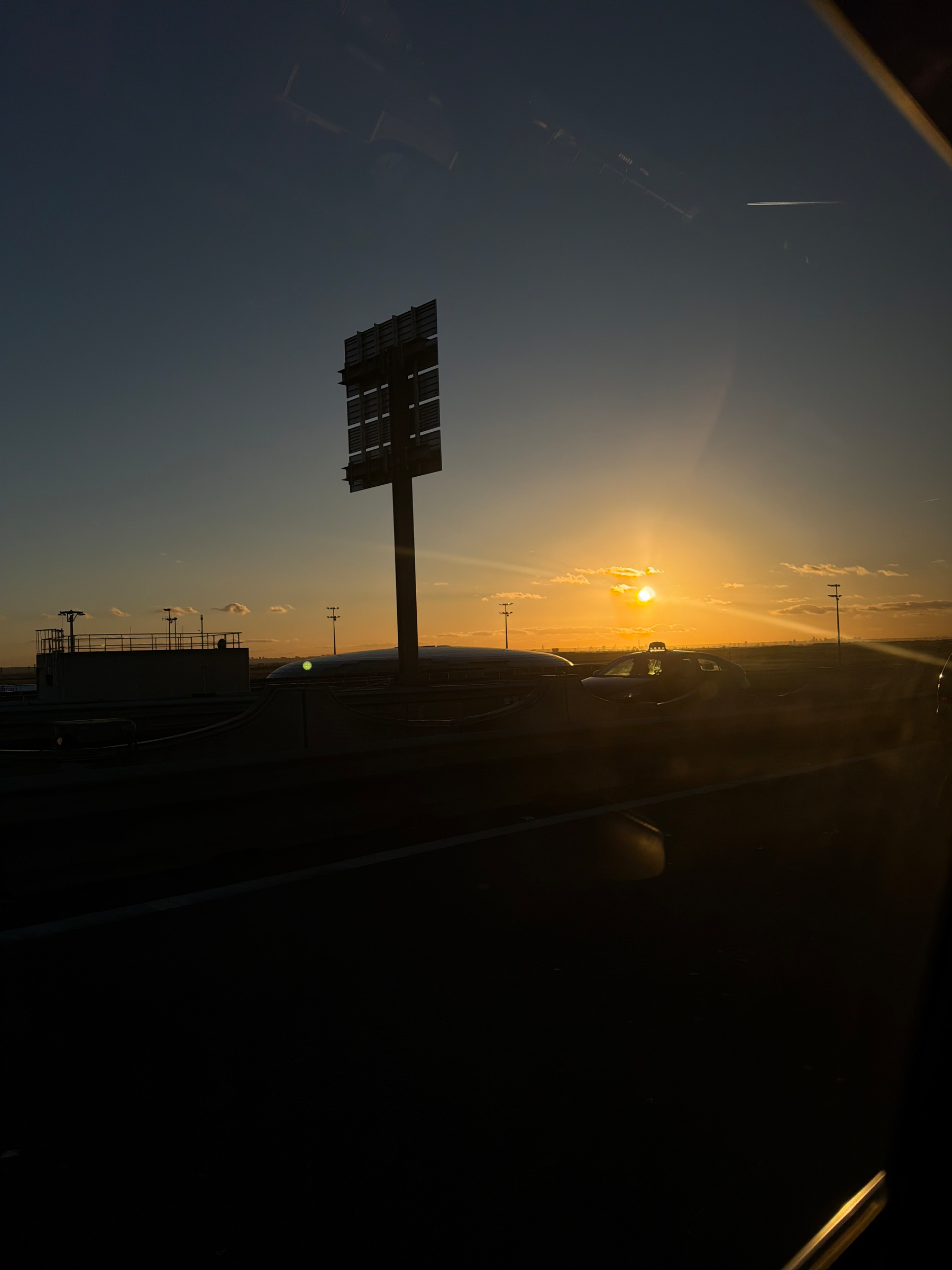 A beautiful sunset casts a warm glow over an outdoor area with silhouetted light poles.