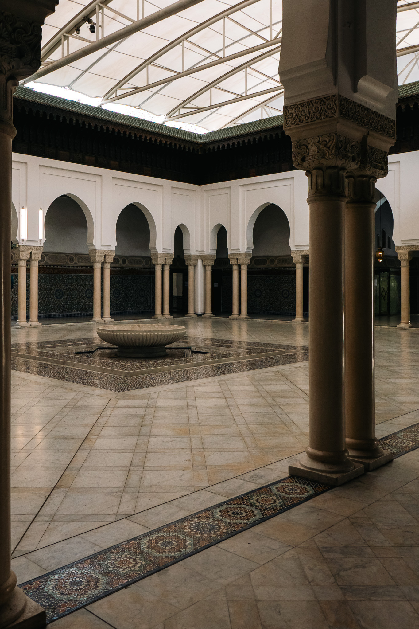 A spacious, ornate courtyard features tall arches, decorative columns, and a central fountain.