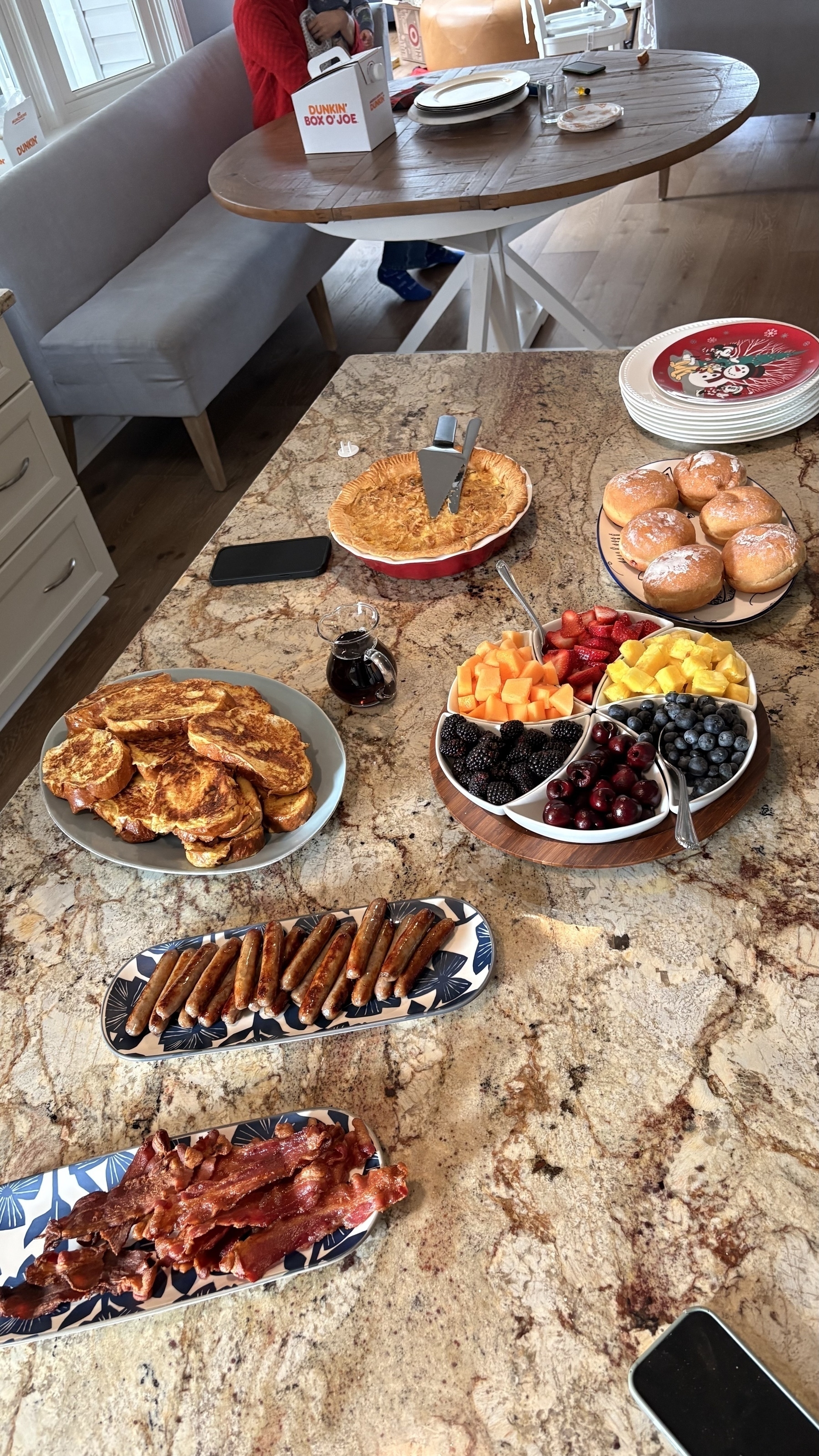 A table is set with a variety of breakfast foods, including French toast, berries, bacon, cinnamon sticks, and pastries.