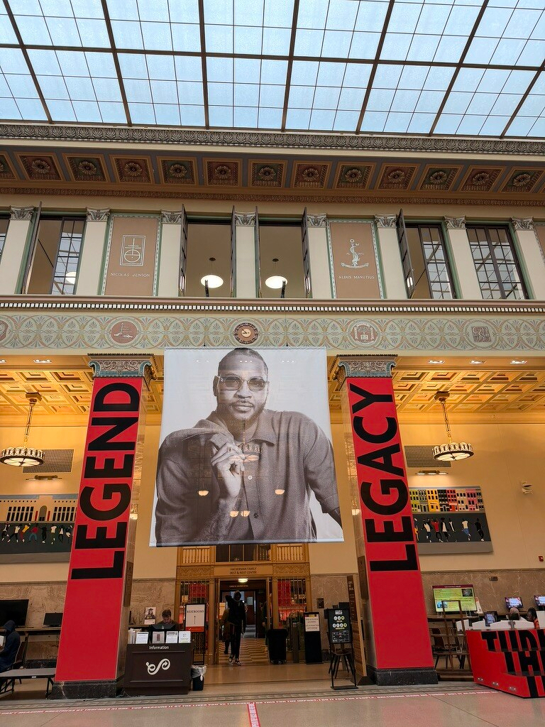 A large photograph and banners with the words Legend and Legacy hang prominently in a spacious, ornate hall.