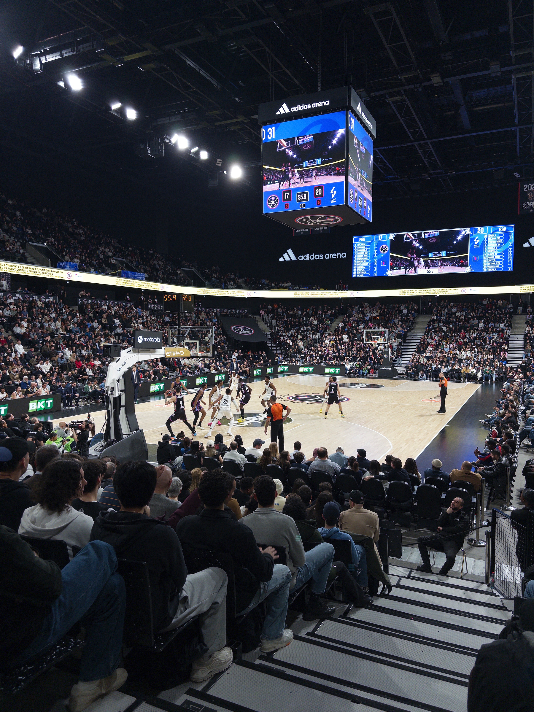 A basketball game is taking place at a crowded indoor arena.