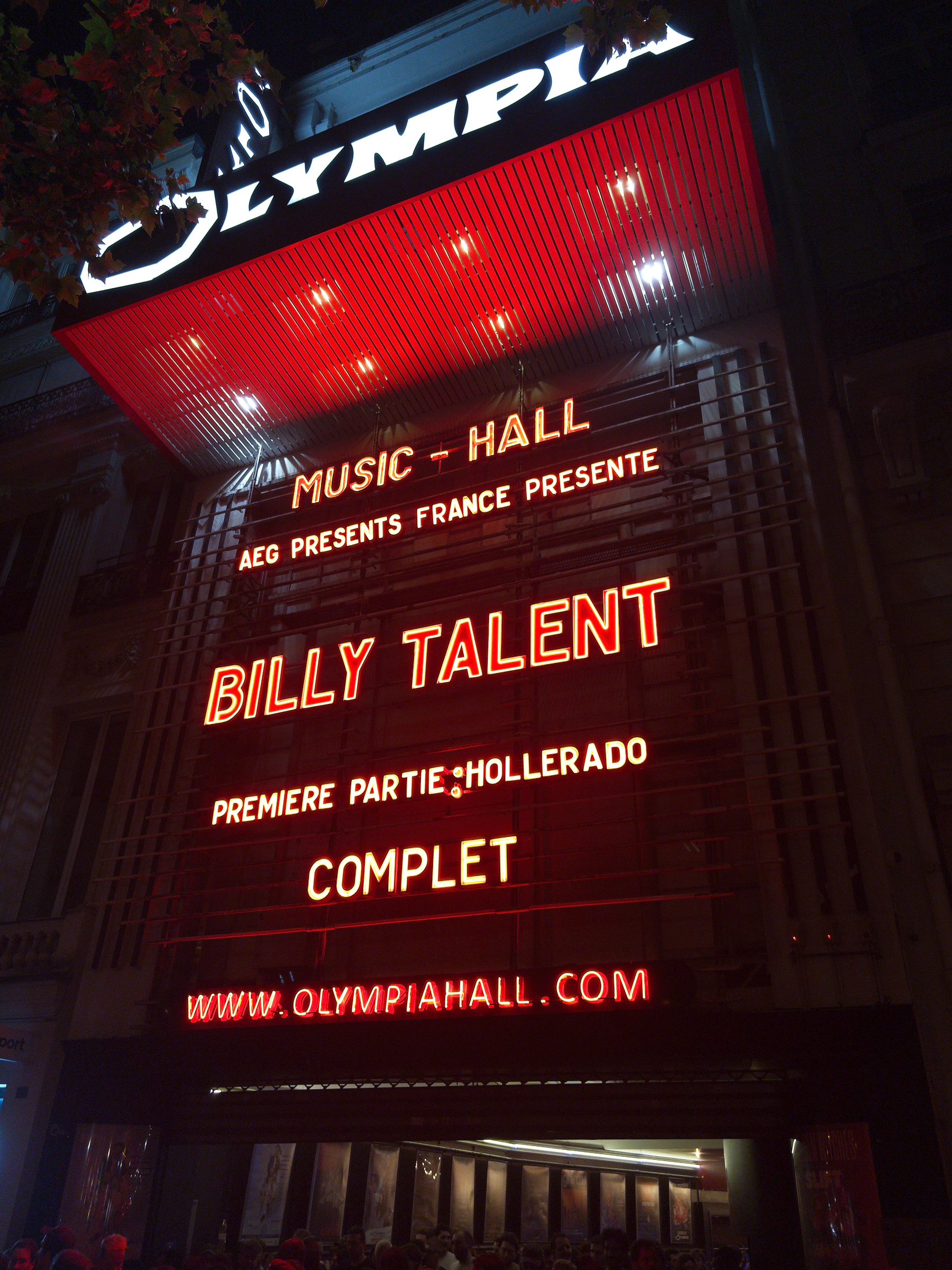 Auto-generated description: A neon-lit sign outside Olympia Hall announces a sold-out Billy Talent concert with support from Hollerado.