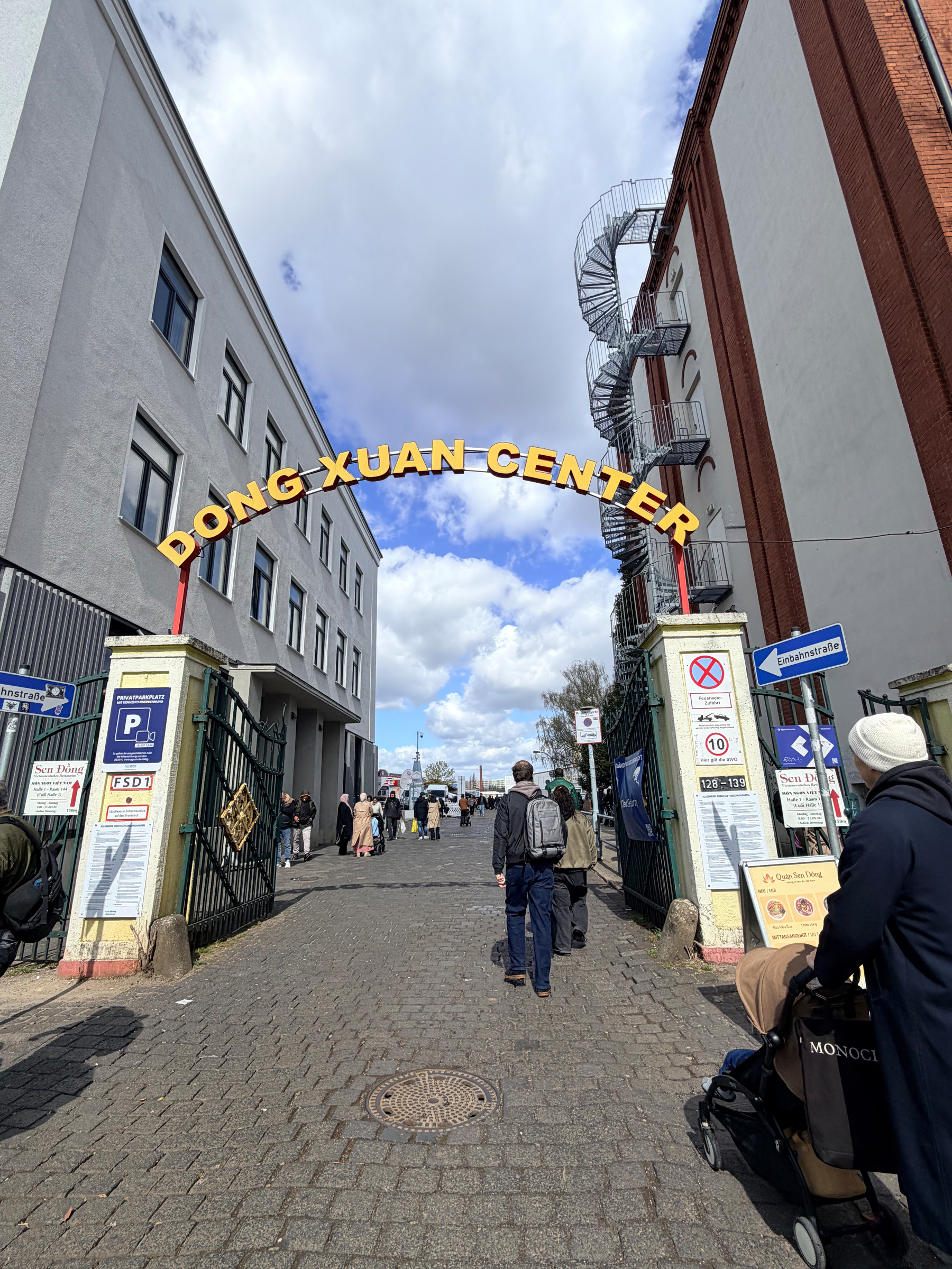 Auto-generated description: People are walking under an archway labeled Dong Xuan Center at the entrance of a market or shopping area.