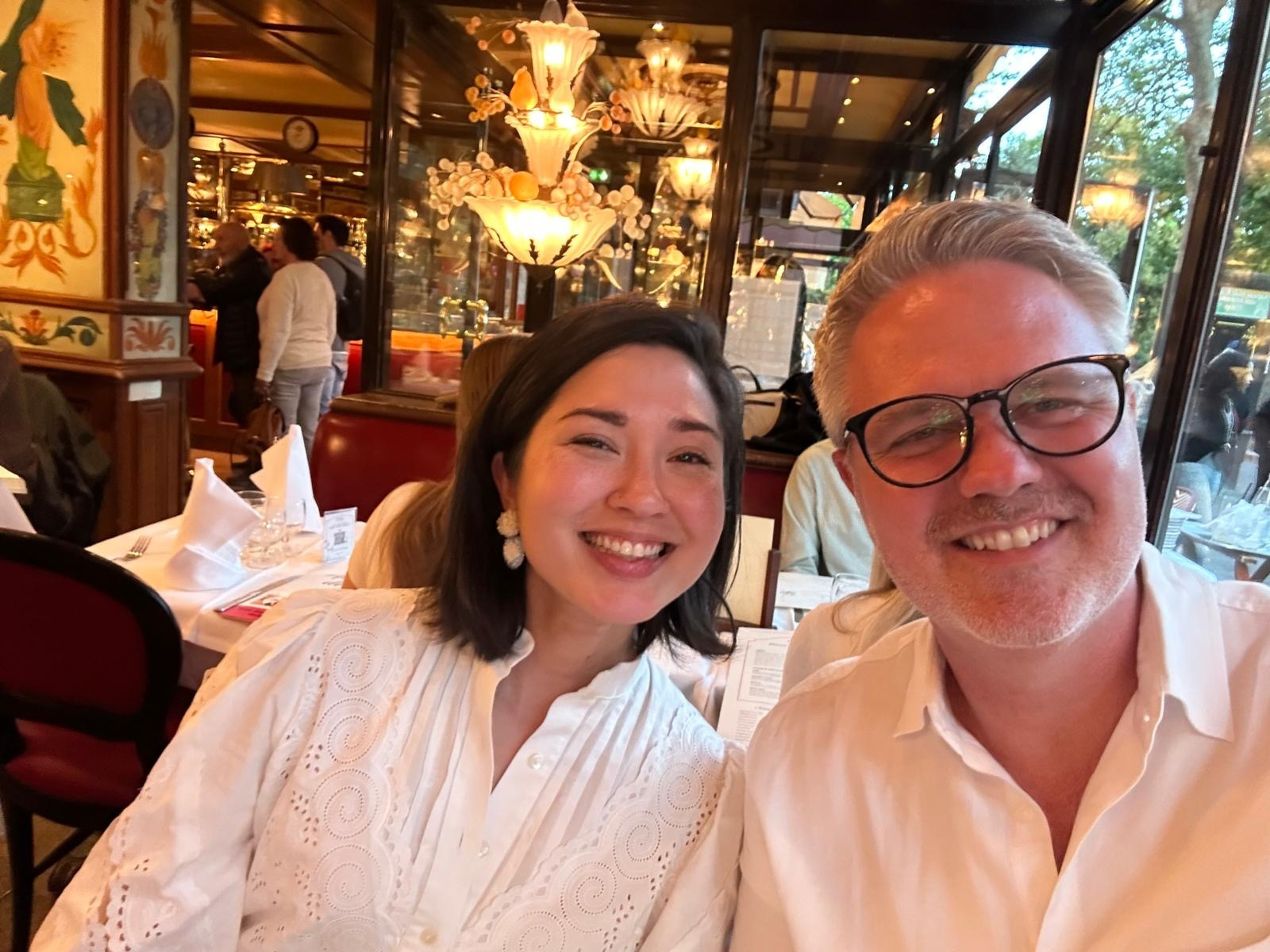 A smiling couple is sitting at a restaurant table, enjoying their time together.