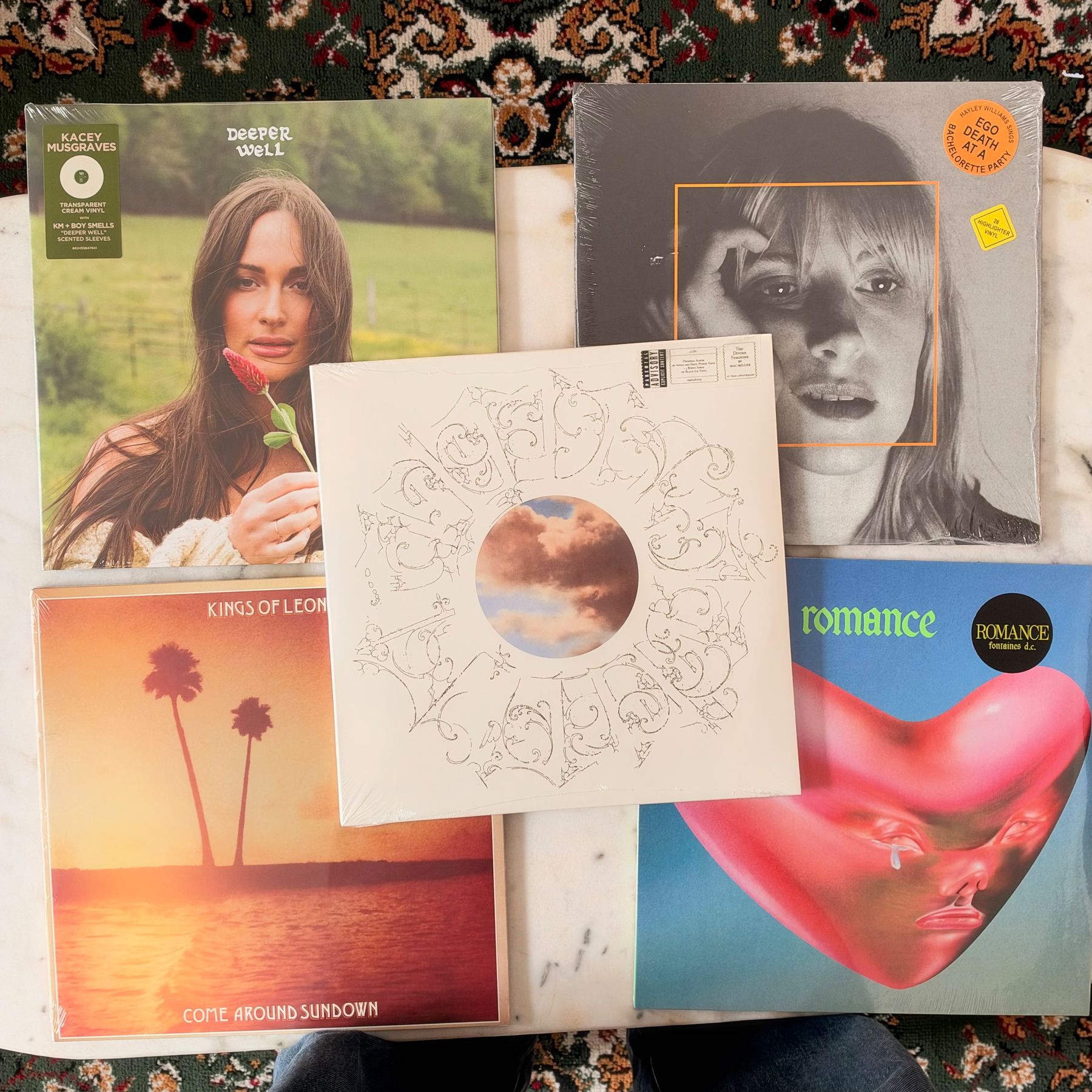 Five vinyl record albums with various cover designs are arranged on a white surface, featuring artists such as Macey Musgraves, Kings of Leon, and others.