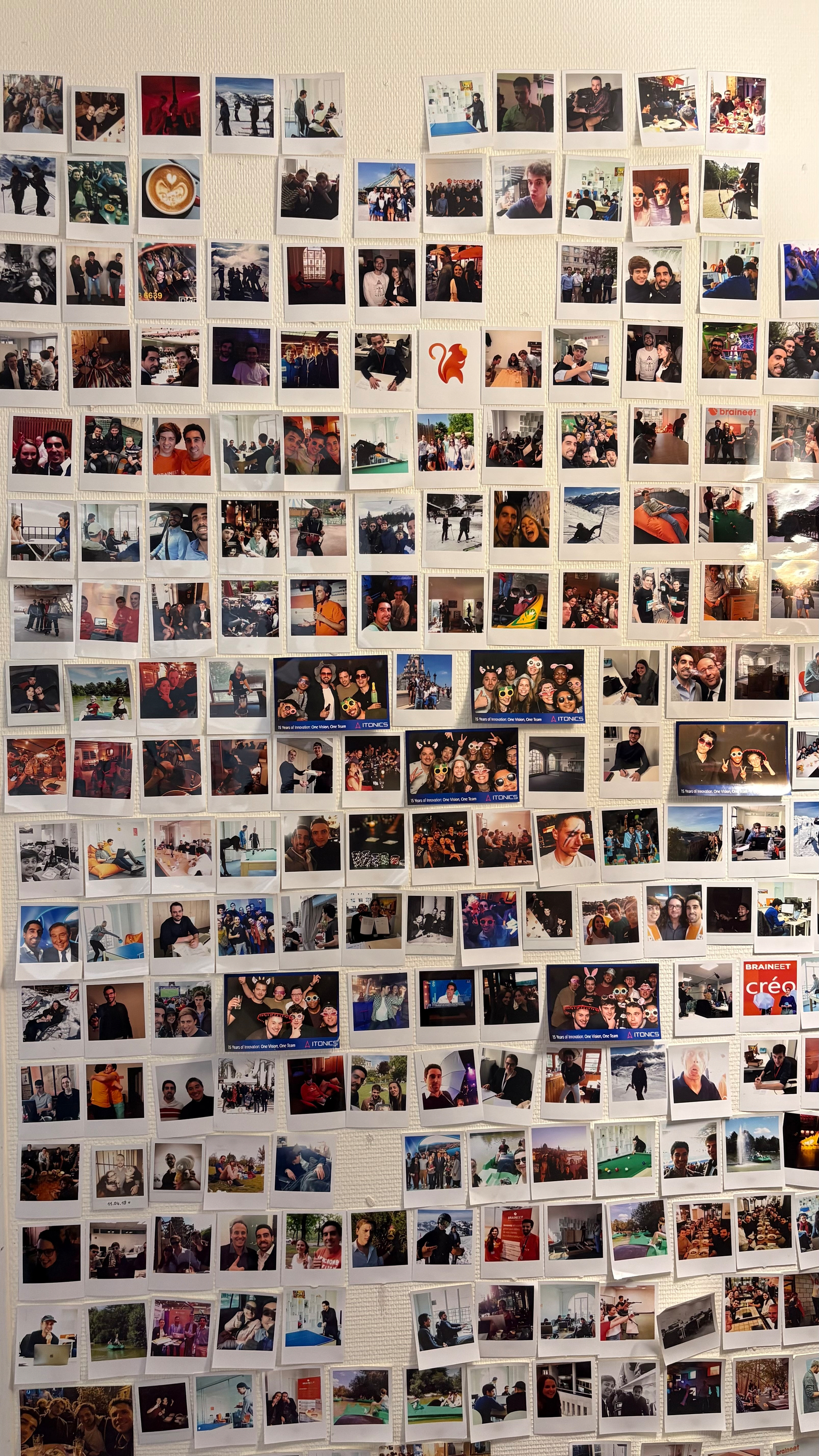 A wall is covered with numerous small photos depicting groups of people, outdoor scenes, social gatherings, and various activities.
