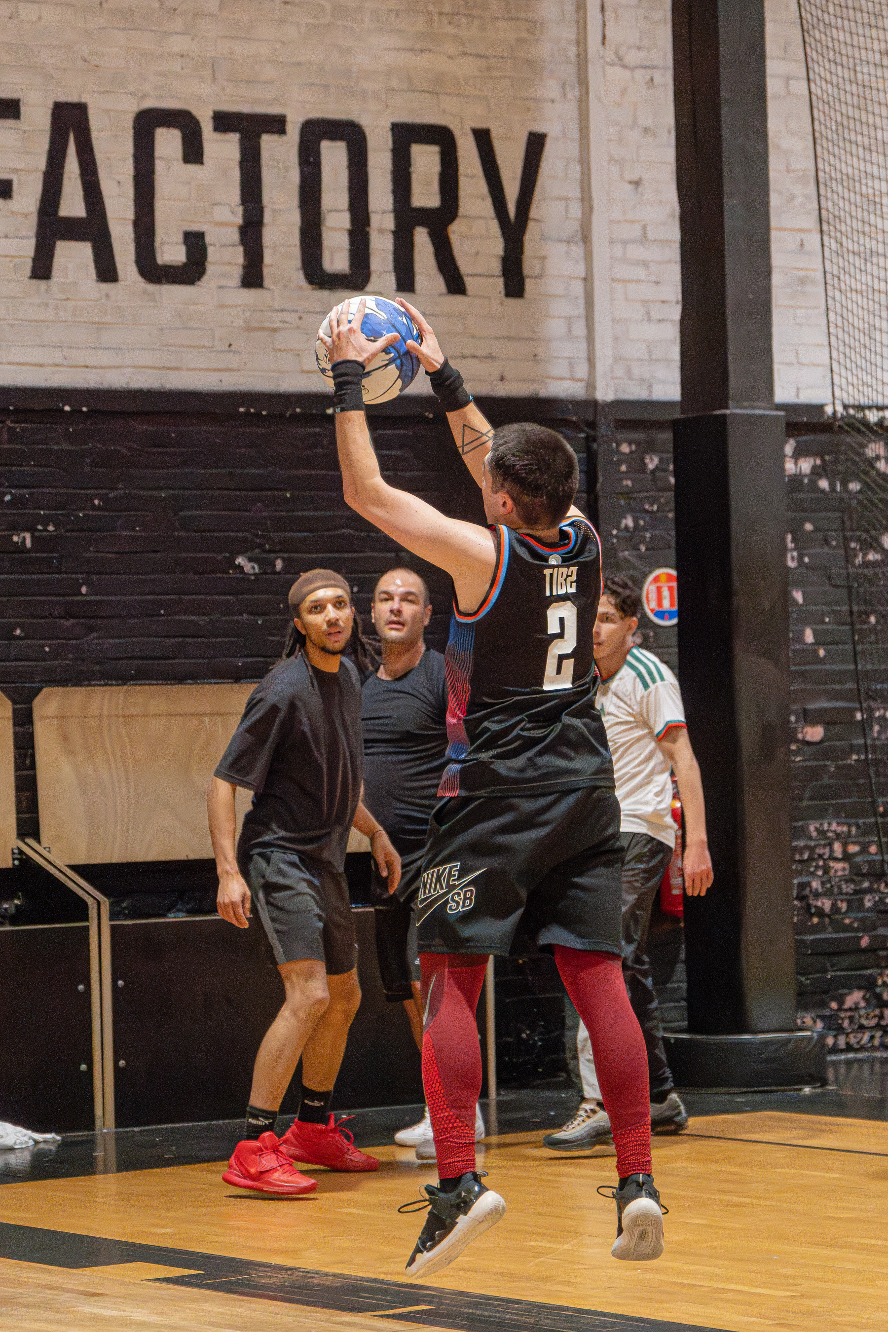 A basketball player, wearing jersey number 2, is preparing to pass the ball to teammates during an indoor game.