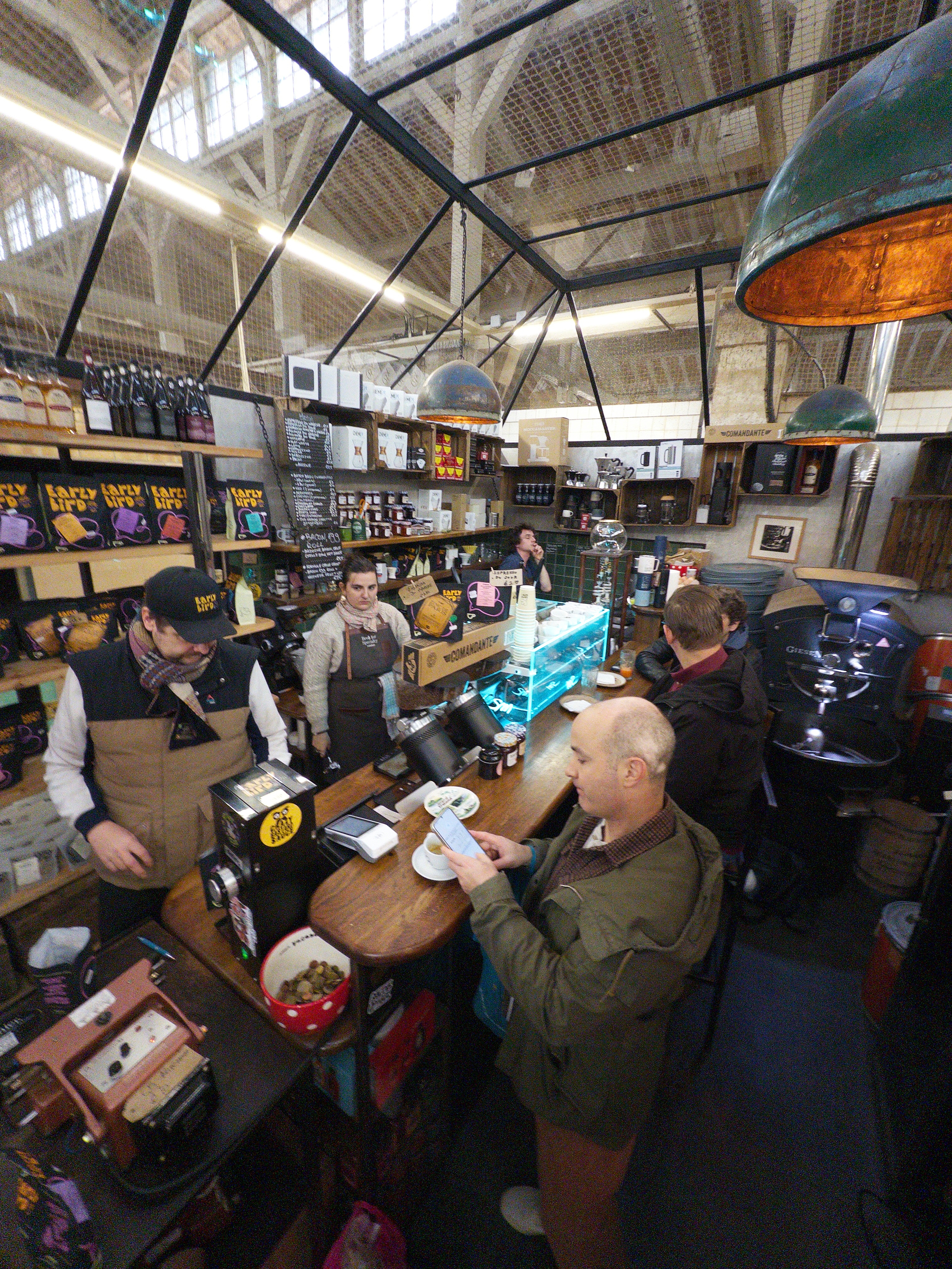 A cozy coffee shop scene shows baristas preparing drinks and customers enjoying their orders at the counter.