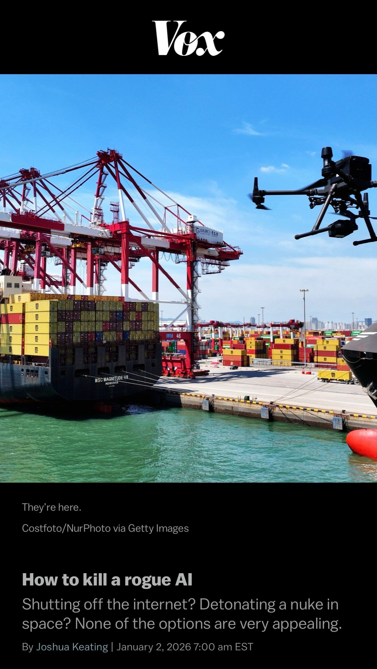 A cargo ship at a port is being observed by a drone flying nearby under a clear blue sky.
