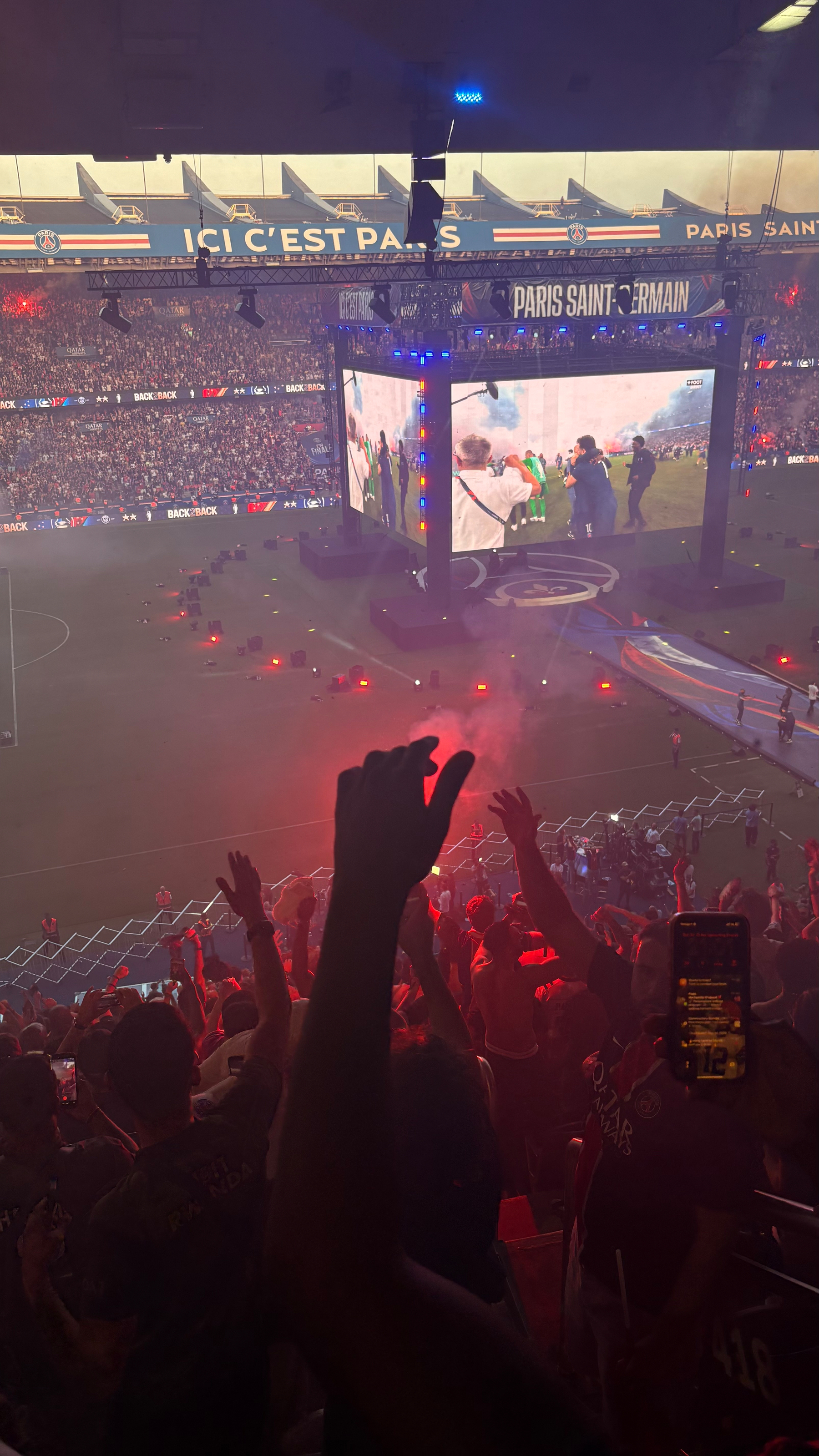 A lively football stadium scene with a cheering crowd, vibrant lights, and a large screen displaying action on the field.