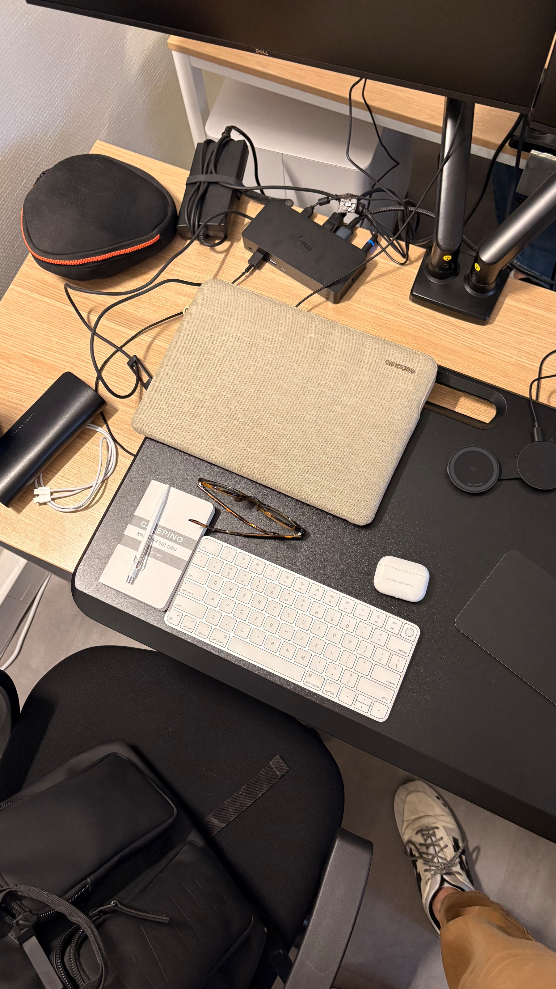 A workspace features a desk with electronic accessories, a keyboard, mouse, glasses, and a closed laptop.