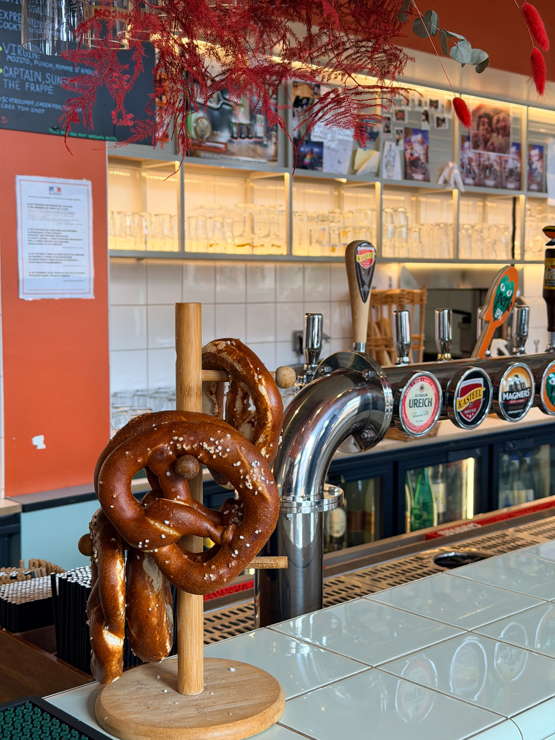 A pretzel stand is situated on a countertop in a colorful bar with various beer taps and glassware in the background.