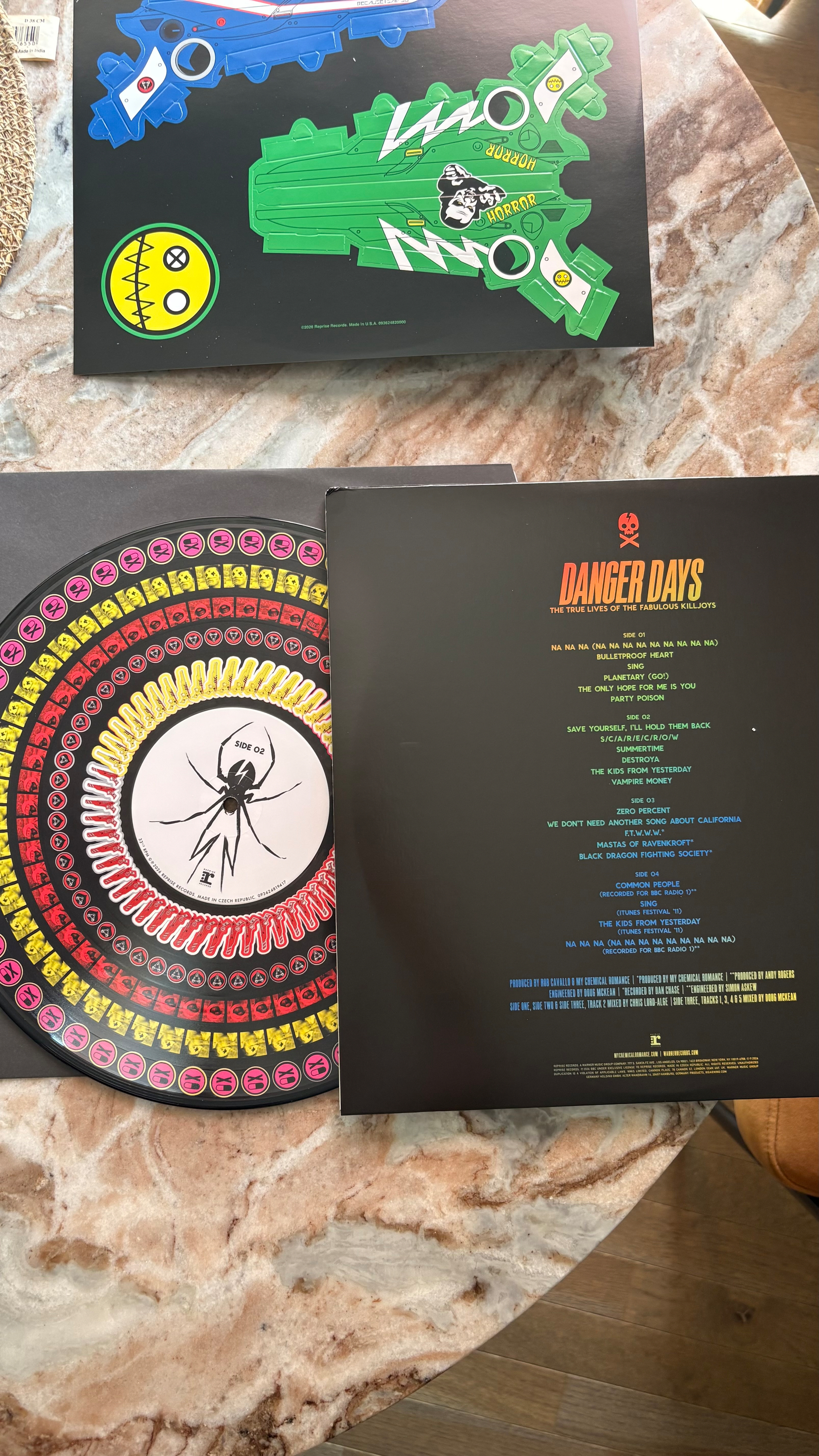 A vinyl record of My Chemical Romance's album Danger Days: The True Lives of the Fabulous Killjoys is shown along with colorful, graphic art pieces related to the album's theme.